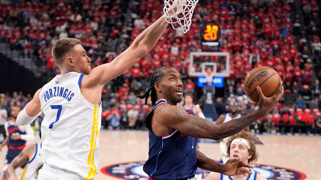 LA Clippers forward Kawhi Leonard, center, shoots as Golden State Warriors center Kristaps Porzingis defends during the first half of an NBA play-in tournament basketball game Wednesday, April 15, 2026, in Inglewood, Calif.