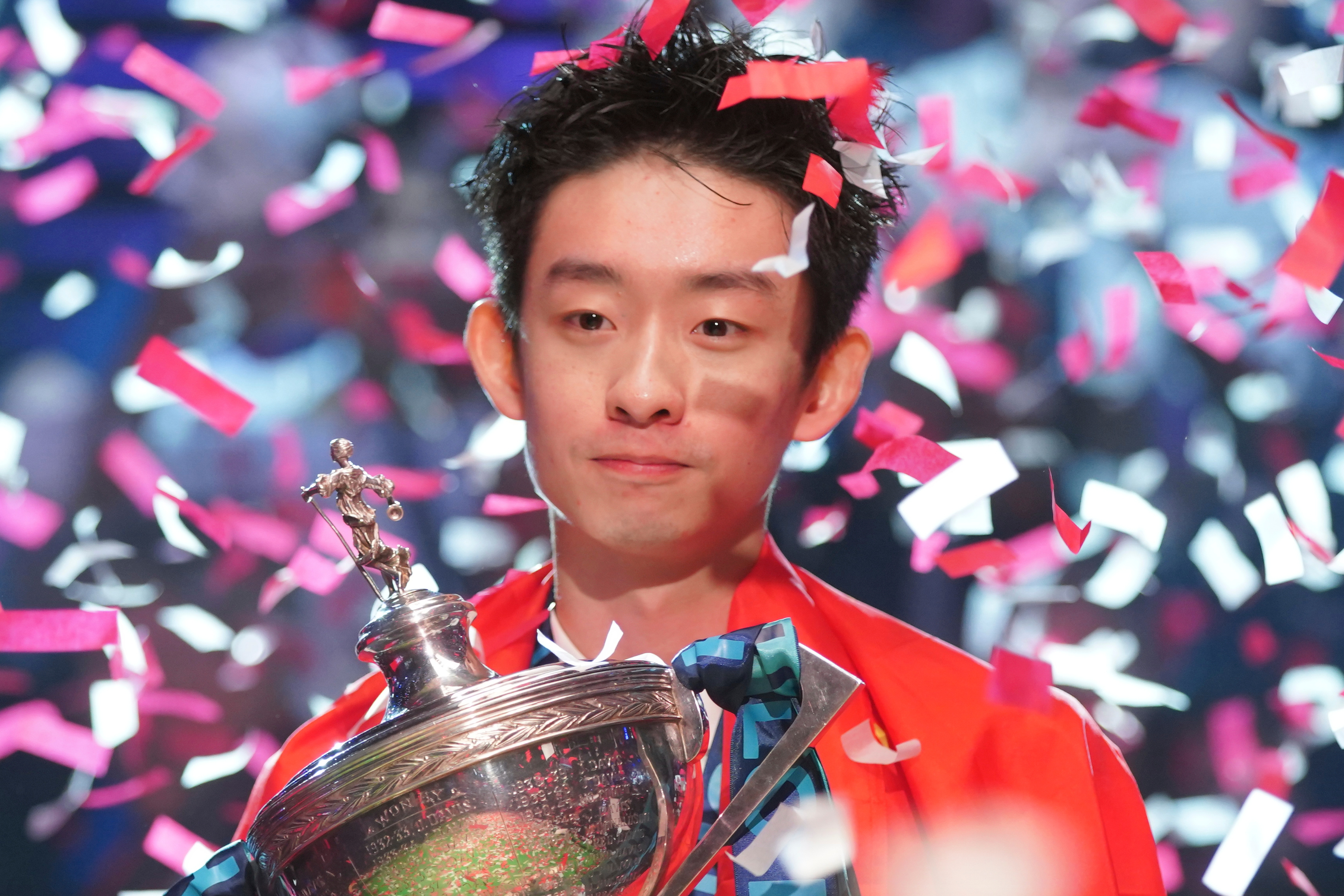 China's Wu Yize poses for the media with the trophy and wearing the Chinese national flag, after winning the World Snooker Championship defeating England's Shaun Murphy in Sheffield, England, Monday, May 4, 2026.