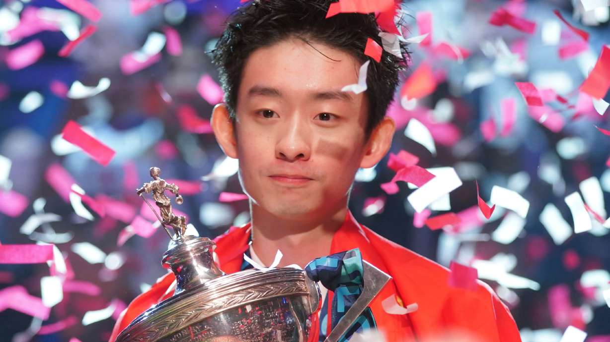 China's Wu Yize poses for the media with the trophy and wearing the Chinese national flag, after winning the World Snooker Championship defeating England's Shaun Murphy in Sheffield, England, Monday, May 4, 2026.