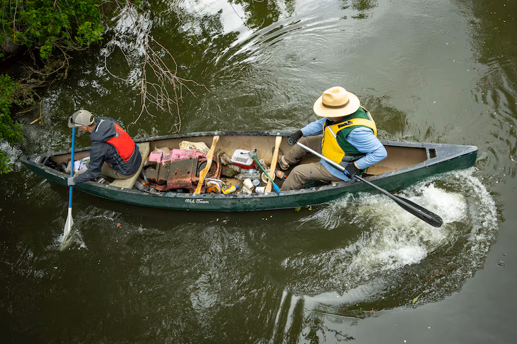 Sam Taylor and Carl Adams pick up trash along the banks of the Jordan River on April 22, 2026, as the Jordan River Commission hosted an Earth Day cleanup.