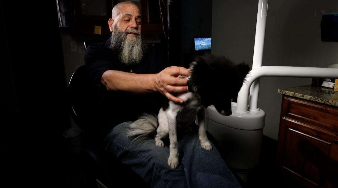 Charles Cribbs pets Eberle, an Irish Pomeranian dog. Anxious patients are being coaxed into the chair at the dentist’s office by a new kind of dental assistant, dental therapy dogs.