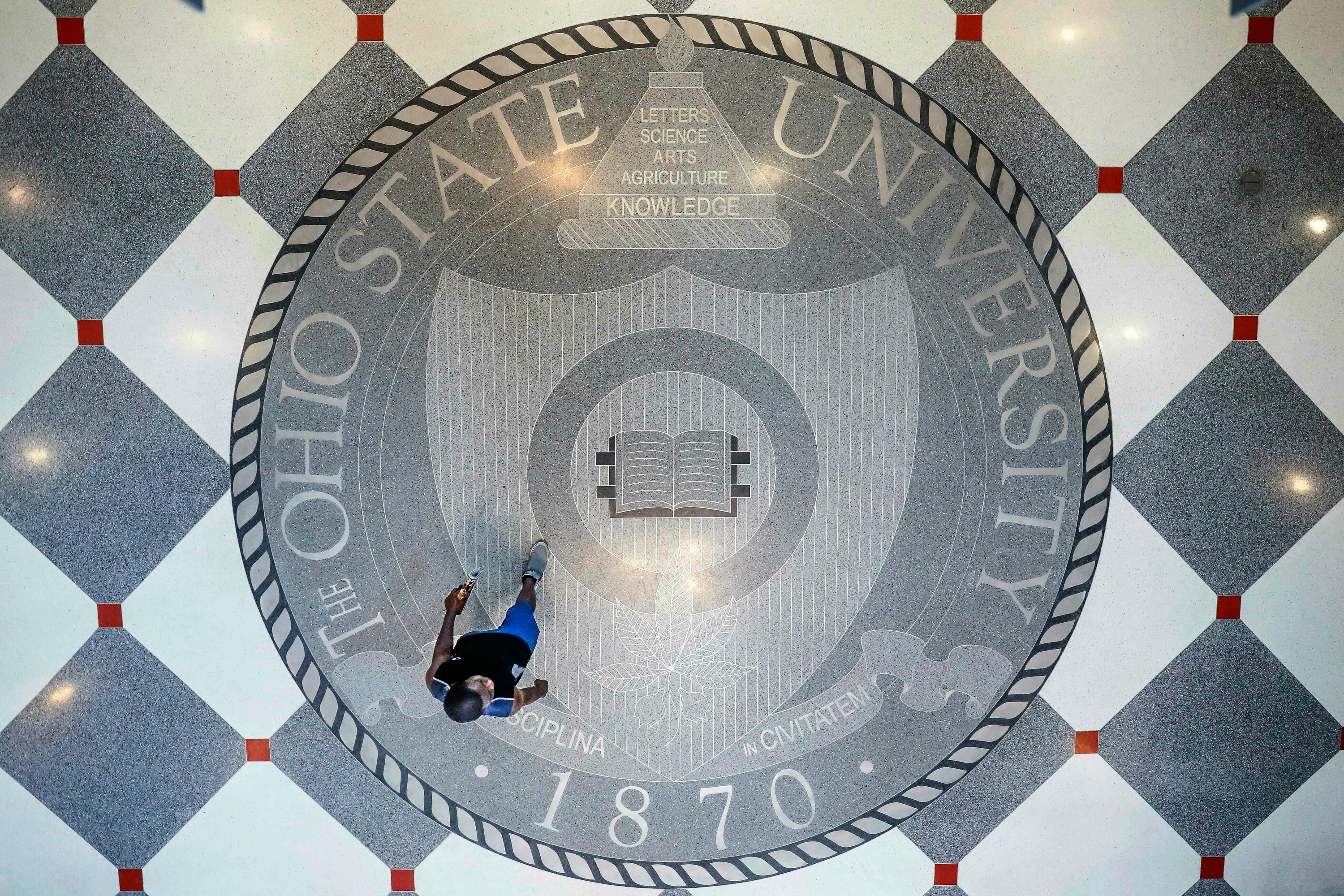 FILE - A person walks over the Ohio State University's emblem in the campus student union, May 18, 2019, in Columbus, Ohio. 