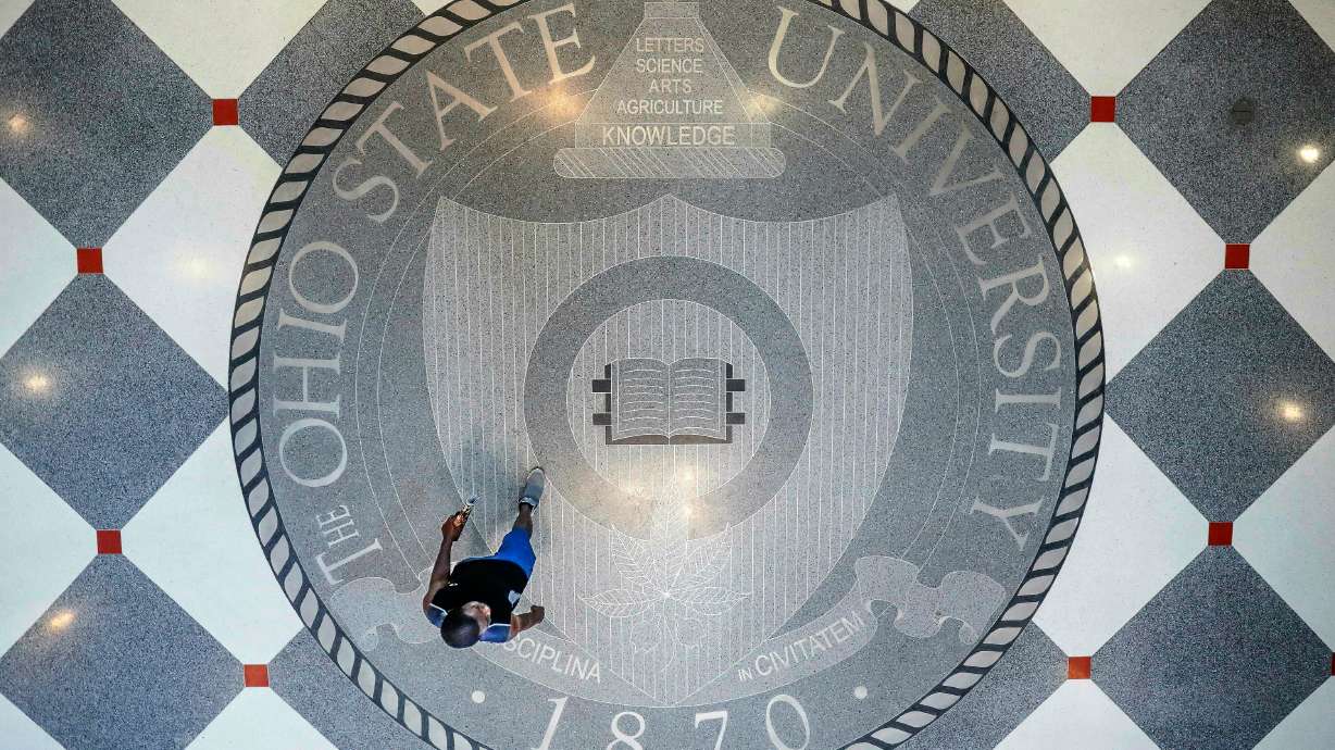 FILE - A person walks over the Ohio State University's emblem in the campus student union, May 18, 2019, in Columbus, Ohio.