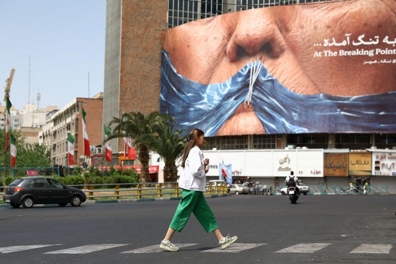 A woman walks past an anti-U.S. billboard depicting President Donald Trump and the Strait of Hormuz, in Tehran, Iran, Friday. A state of relative calm prevailed on Saturday as the U.S. waits for Iran's response to its latest peace proposal.