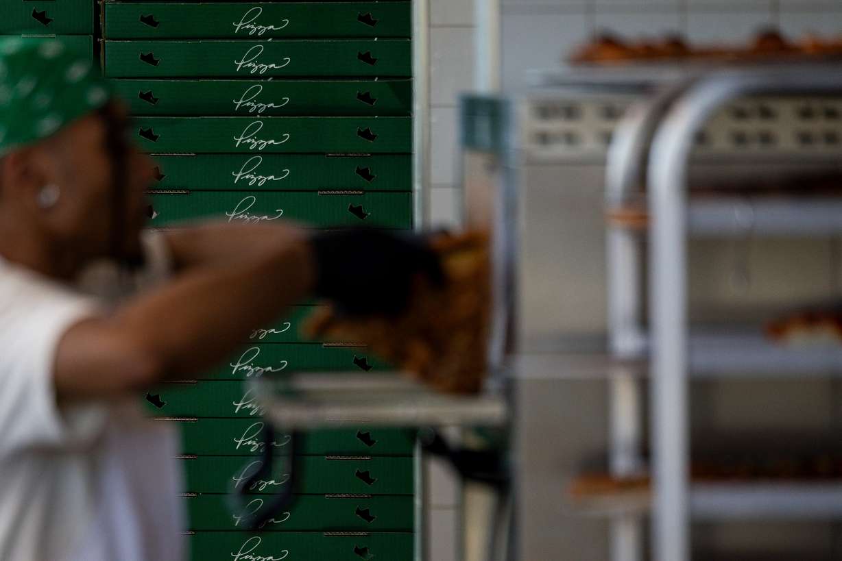 A stack of pizza boxes line the wall as an employee places a slice into the warming oven at Fini Pizza in Vineyard on May 2. The pizzeria was fully sold out on a Monday afternoon just days after opening.