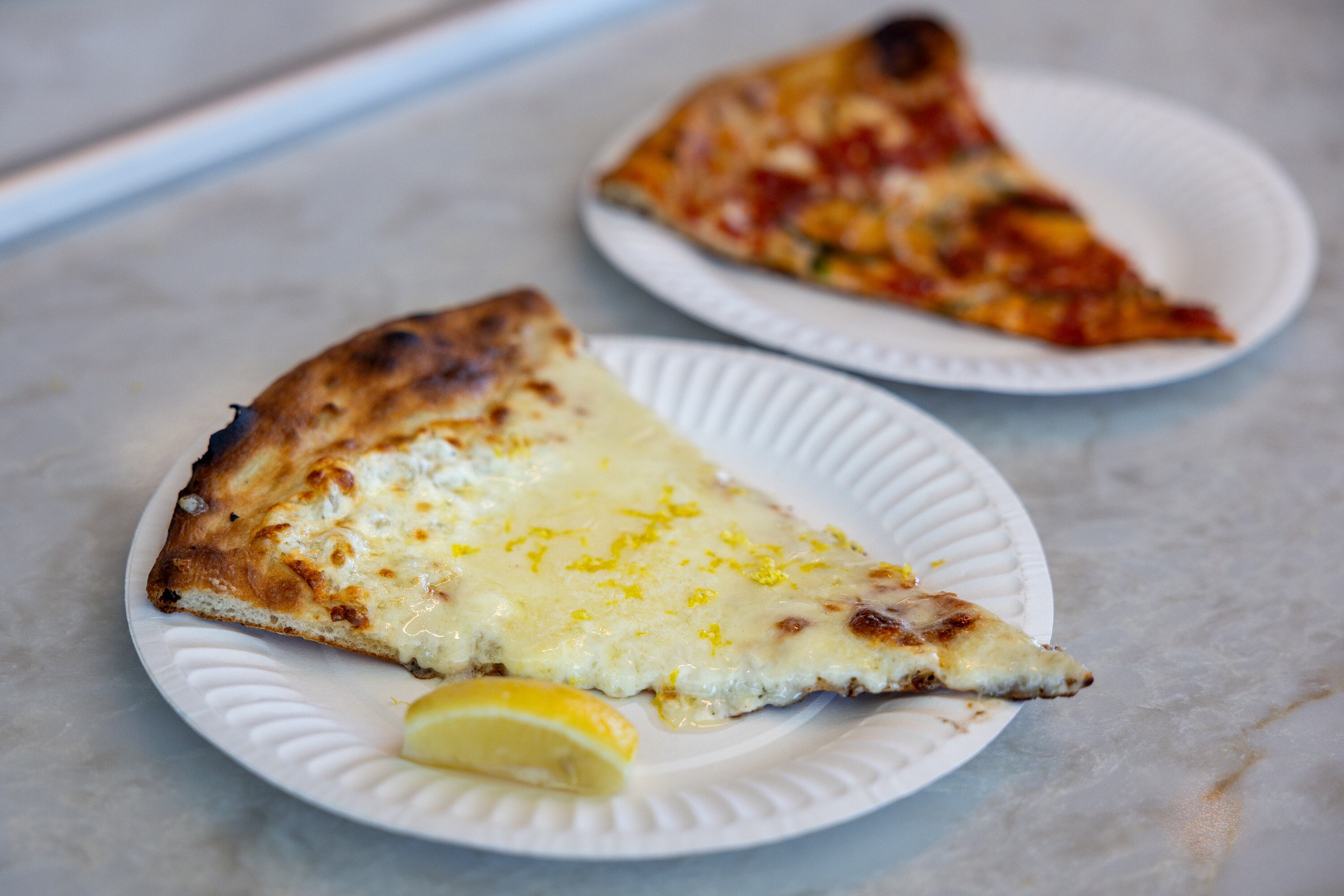 A slice of the NY White Pie and a Sicilian slice sit on a counter at Fini Pizza in Vineyard on May 2. Deseret News writer Sarah Gambles ordered both — a slice of Sicilian and a whole white pizza to share with her sister — when she visited the restaurant.