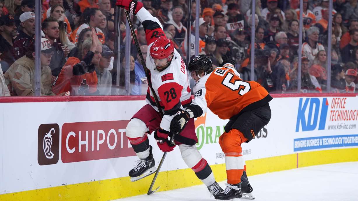 Carolina Hurricanes' William Carrier, left, tries to get past Philadelphia Flyers' Oliver Bonk, right, during the third period of Game 4 in a second-round NHL hockey Stanley Cup playoff series Saturday, May 9, 2026, in Philadelphia.