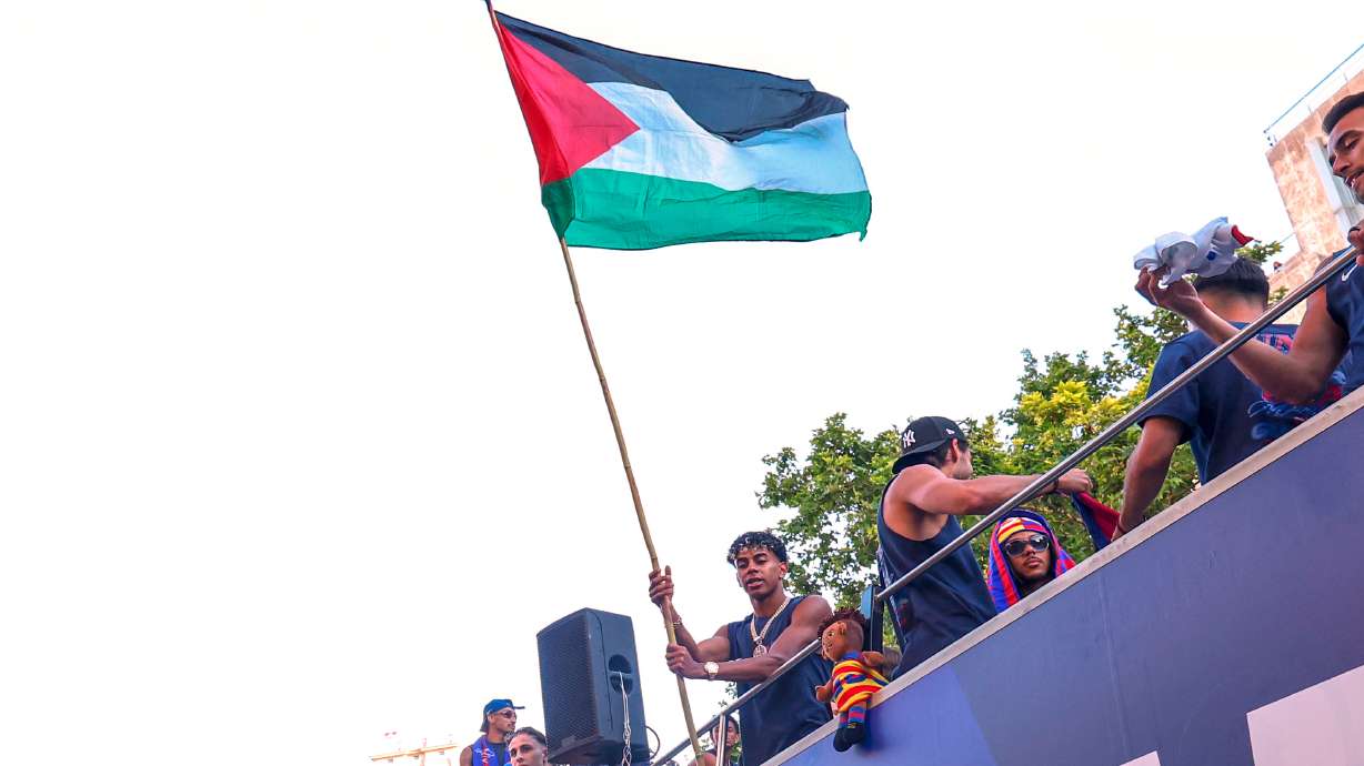FC Barcelona player Lamine Yamal holds a Palestinian flag as he celebrates with his team atop a bus after winning the Spanish La Liga title in Barcelona, Spain, Monday, May 11, 2026.