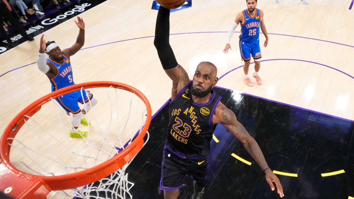 Los Angeles Lakers forward LeBron James, center, goes up for a dunk as Oklahoma City Thunder guard Luguentz Dort, left, and guard Ajay Mitchell watch during the second half of Game 4 in a second-round NBA basketball playoffs series Monday, May 11, 2026, in Los Angeles.