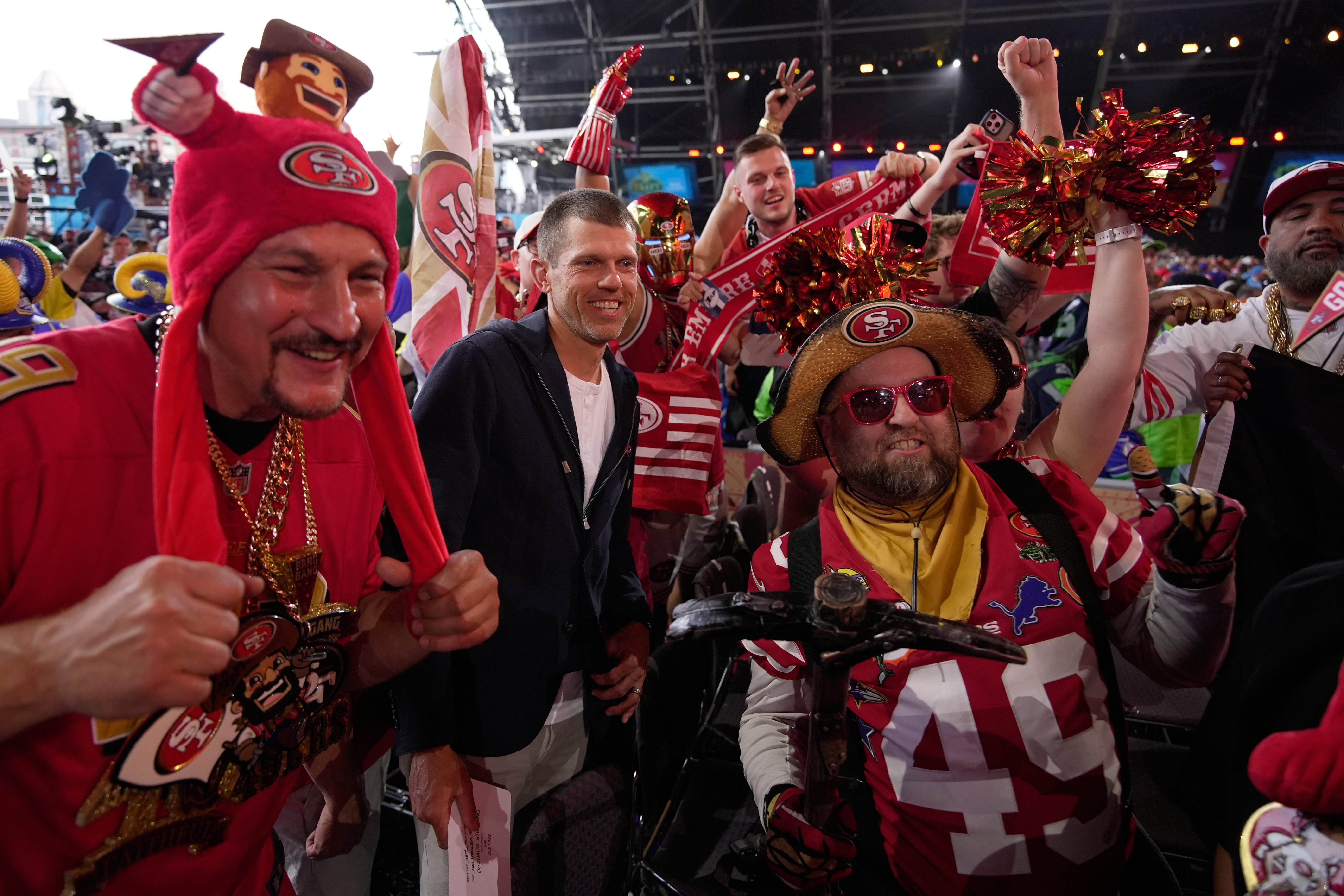 Former NFL player Andy Lee, center, poses with San Francisco 49ers fans during the second round of the NFL football draft, Friday, April 24, 2026, in Pittsburgh.