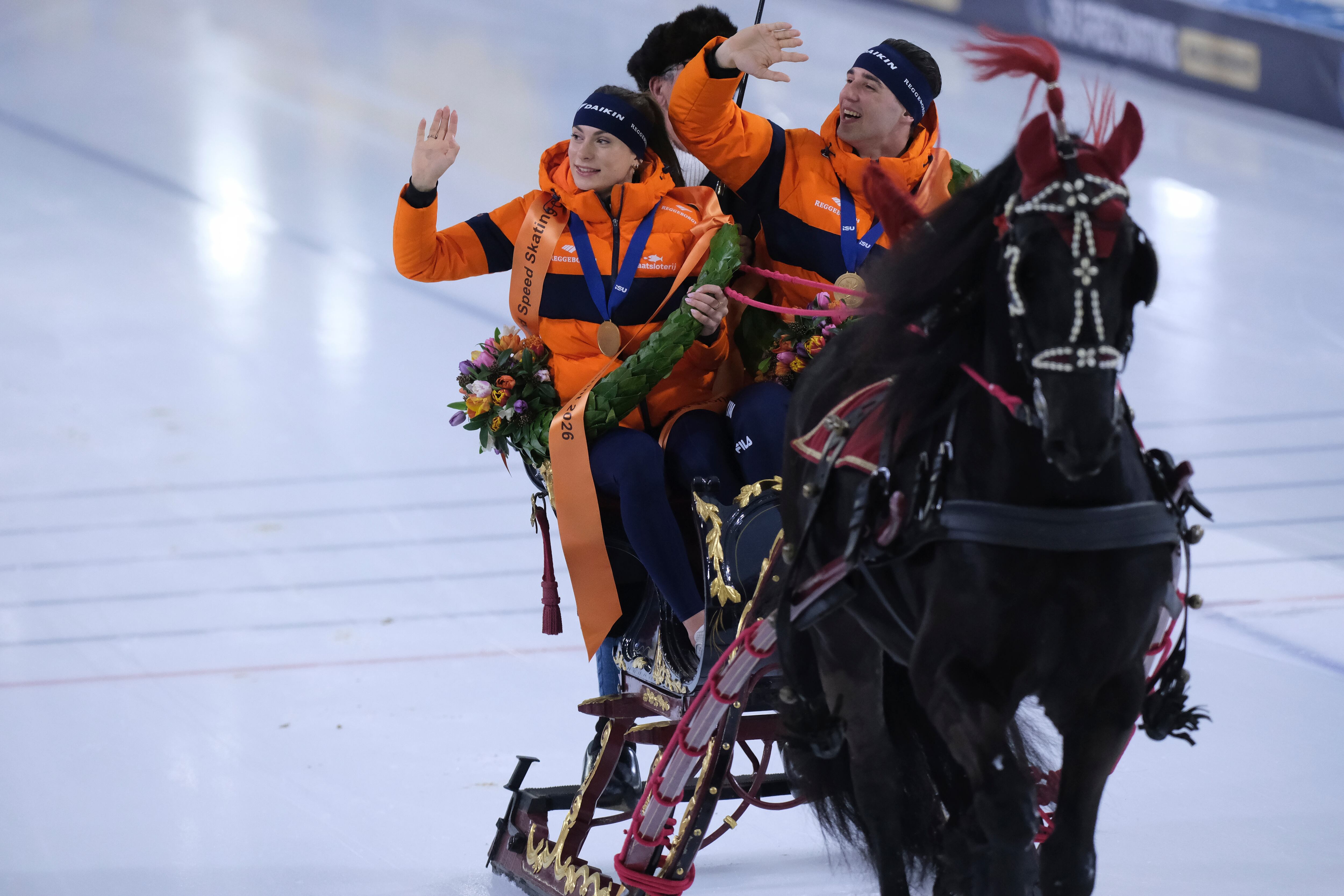 Femke Kok of the Netherlands and Jenning de Boo of the Netherlands ride a lap of honor in a horse-pulled sled after winning the World Championships Sprint in Heerenveen, Netherlands, March 8.
