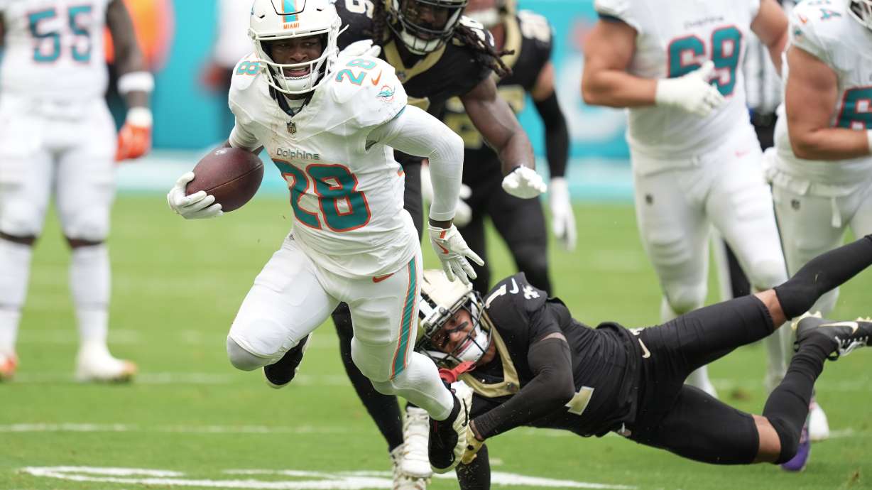 FILE - Miami Dolphins running back De'Von Achane (28) escapes a tackle by New Orleans Saints cornerback Alontae Taylor (1) during the first half of an NFL football game, Nov. 30, 2025, in Miami Gardens, Fla.