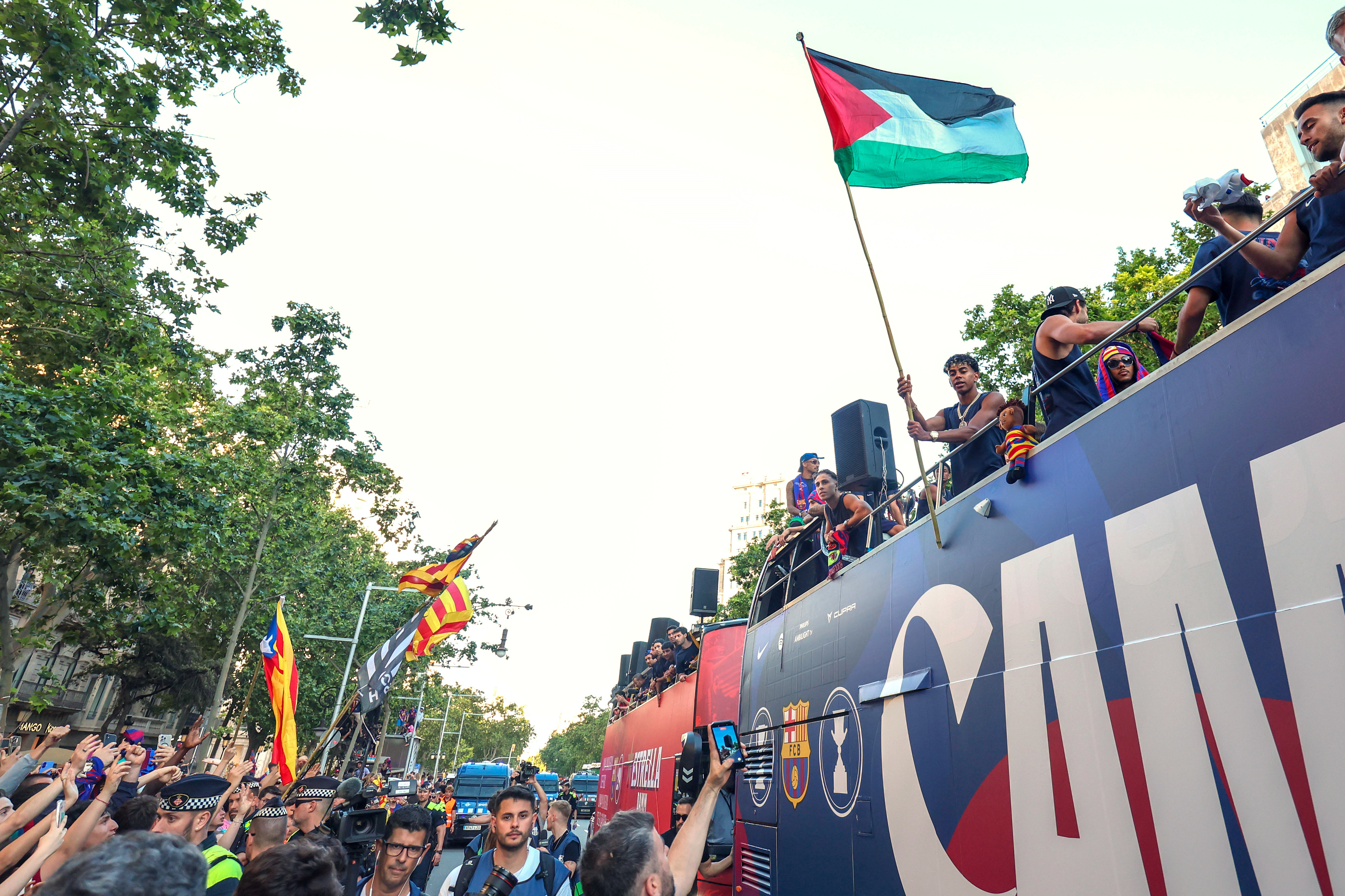 FC Barcelona player Lamine Yamal holds a Palestinian flag as he celebrates with his team atop a bus after winning the Spanish La Liga title in Barcelona, Spain, Monday, May 11, 2026.