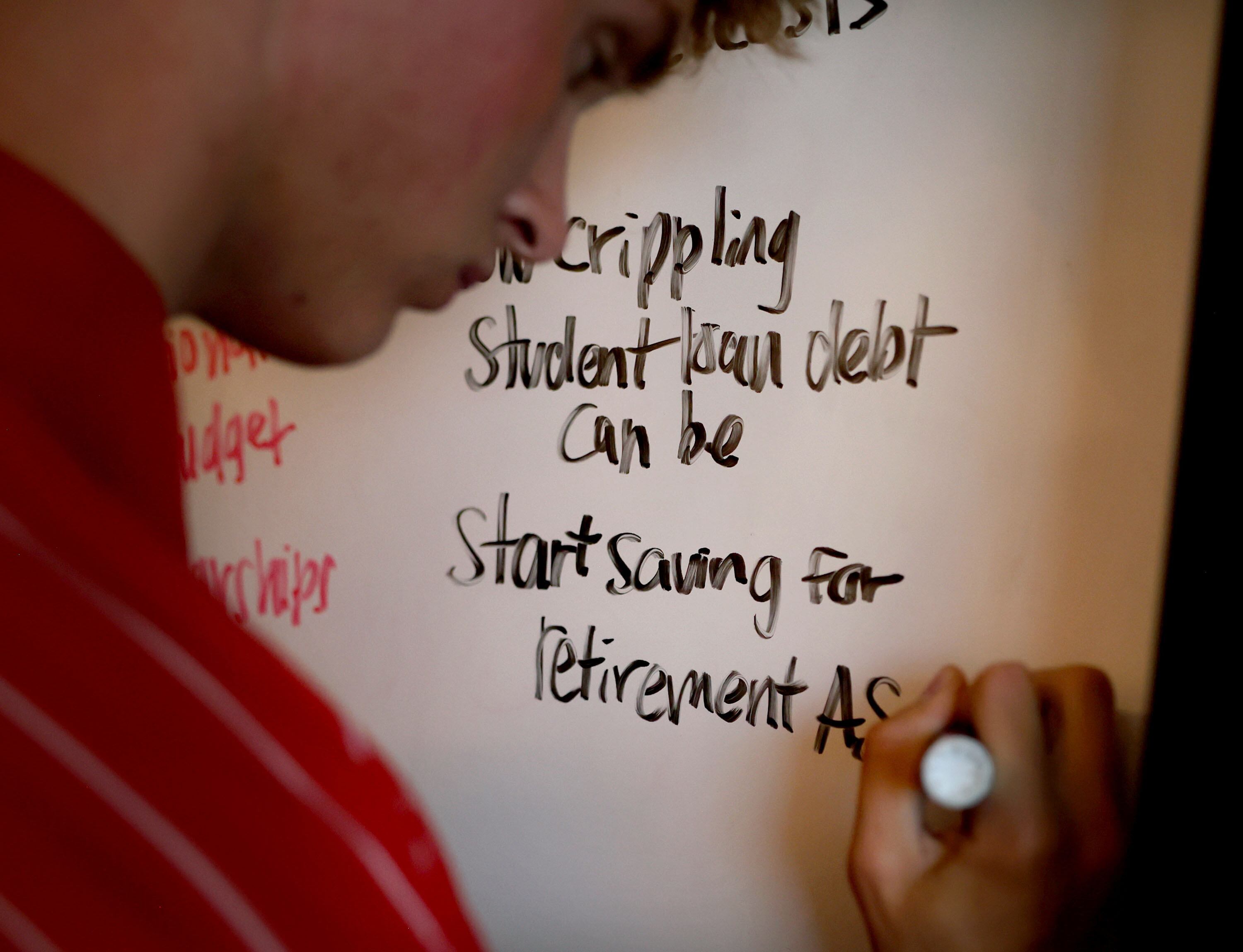 James Robbins jots down what he has learned in Michelle Butler's financial literacy class at Brighton High School in Cottonwood Heights on Thursday.