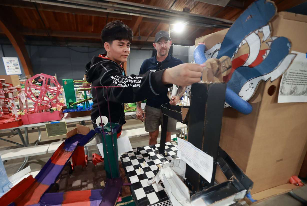Pacific Heritage Academy eighth grader Joshua Cortes shows James McKay, Ride Design judge and Janicki Industries project engineer, the model of an amusement park ride made during Utah State University Physics Day at Lagoon Amusement Park in Farmington on Friday. Thousands of teens from Utah, Idaho, Wyoming and Nevada participate in the STEM learning event.