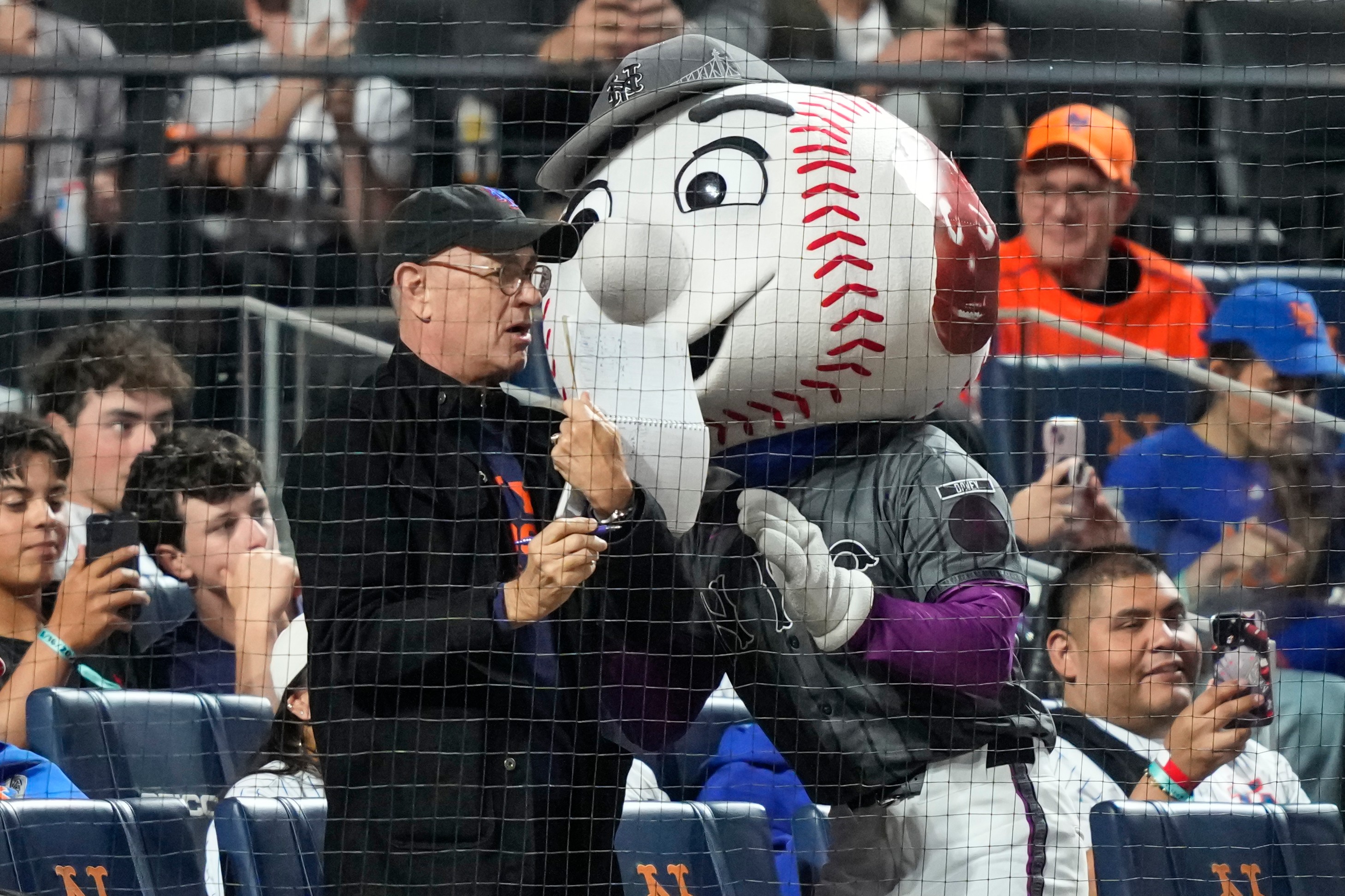 Actor/filmmaker Tom Hanks, center left, stands with Mr. Met, center right, during the sixth inning of a baseball game between the New York Mets and the New York Yankees, Saturday, May 16, 2026, in New York. 