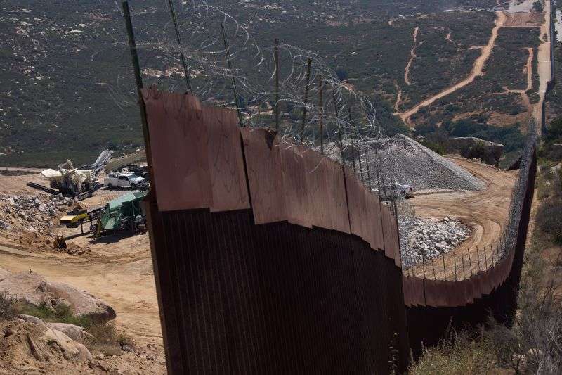 Construction crews work on a new border wall segment near the end of a previously built section on Kuuchamaa Mountain, April 24, seen from Tecate, Mexico.