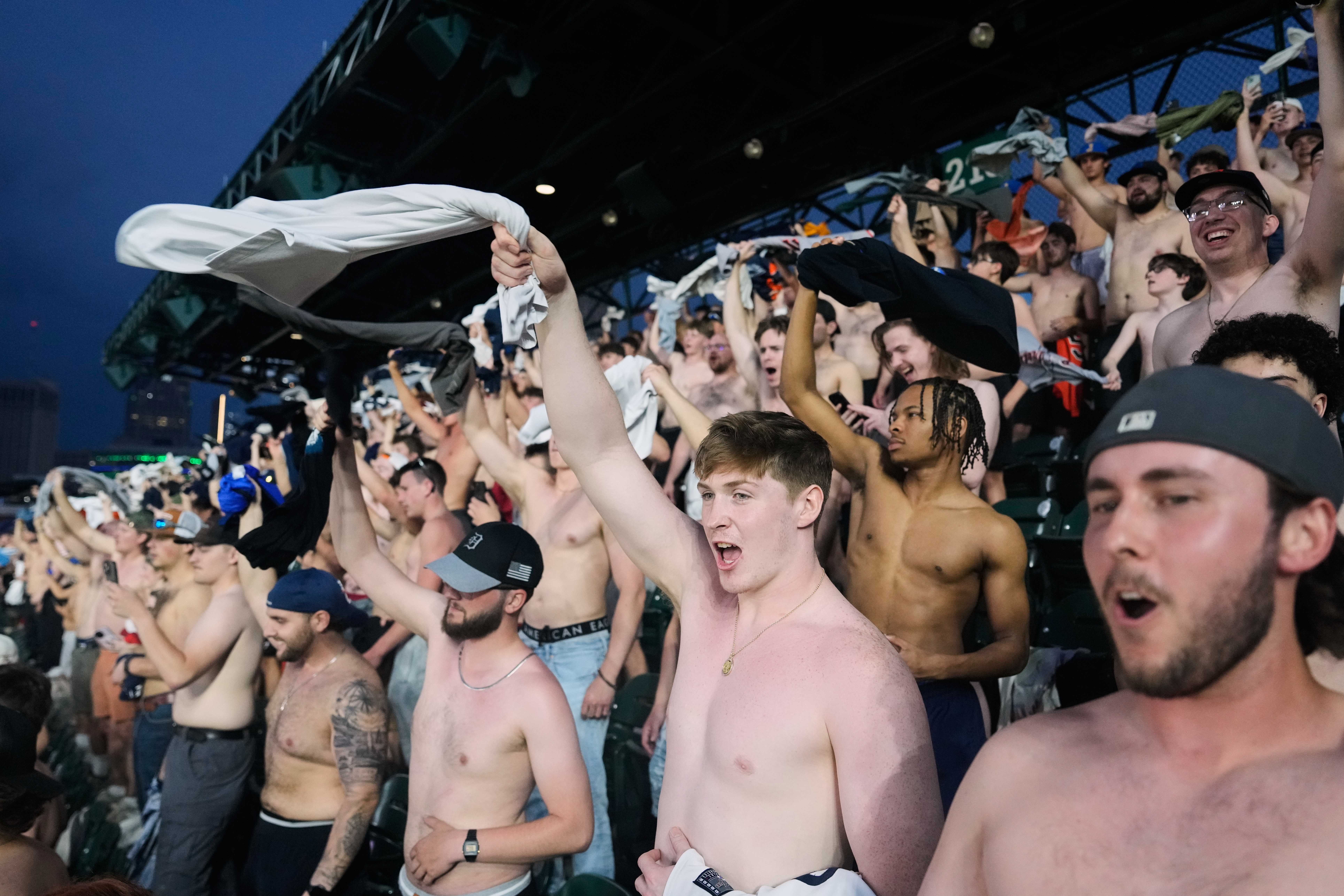 Fans cheer with their shirts off after heading to the upper deck outfield seating during the ninth inning of a baseball game between the Detroit Tigers and Cleveland Guardians Tuesday, May 19, 2026, in Detroit.