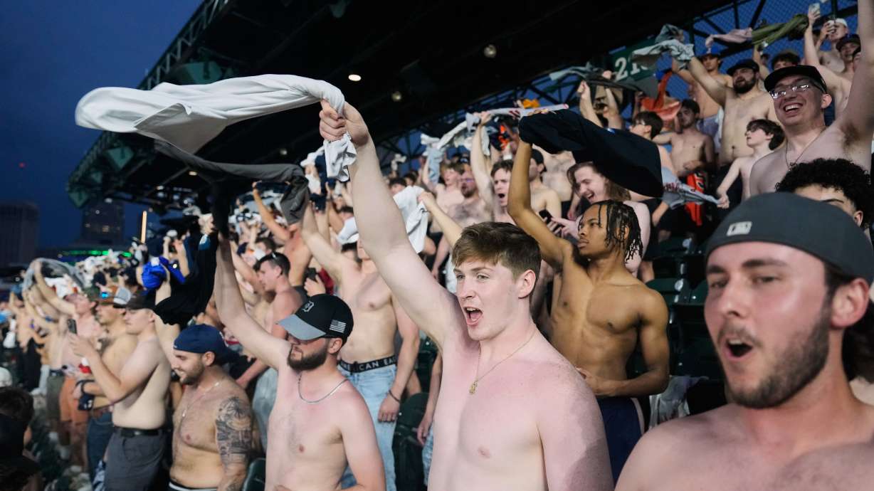 Fans cheer with their shirts off after heading to the upper deck outfield seating during the ninth inning of a baseball game between the Detroit Tigers and Cleveland Guardians Tuesday, May 19, 2026, in Detroit.