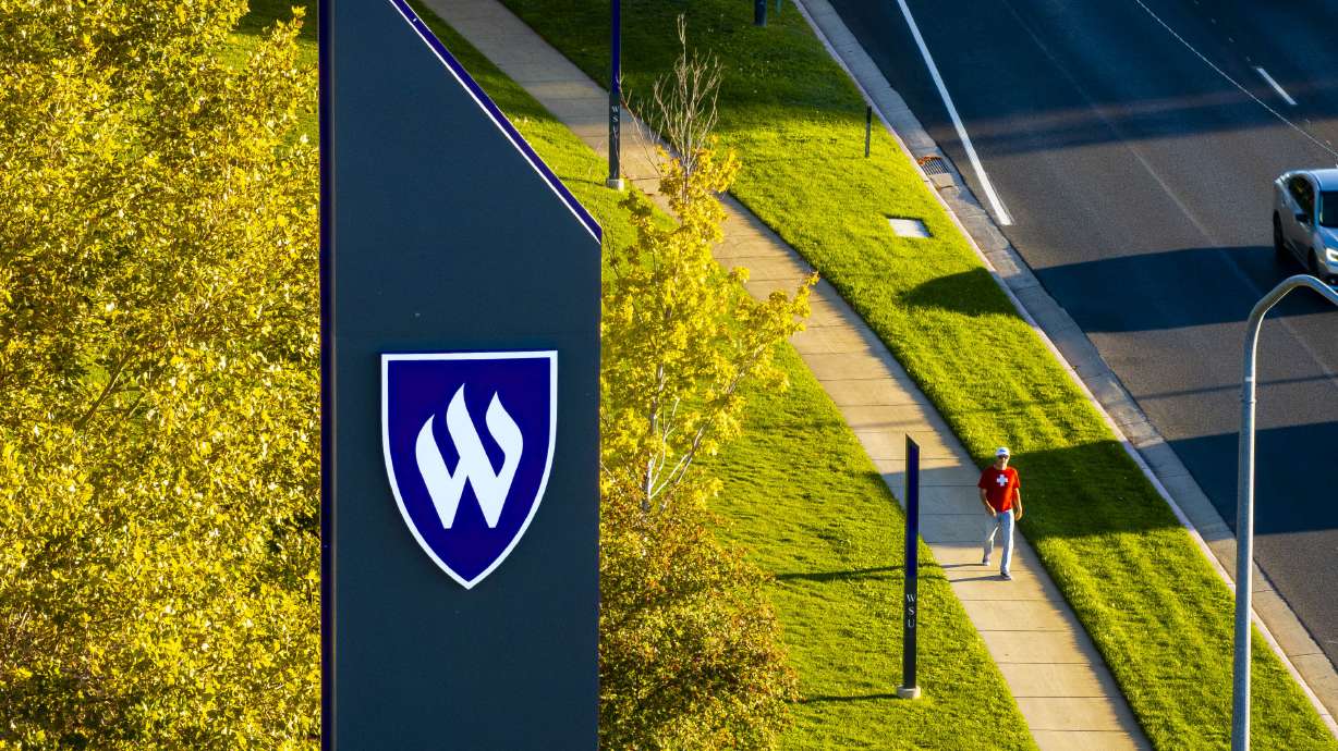 A person walks past signage for Weber State University on the edge of campus in Ogden on Oct. 1, 2025. The Utah Board of Higher Education on Thursday unanimously appointed Chris Mallet as WSU's next president.