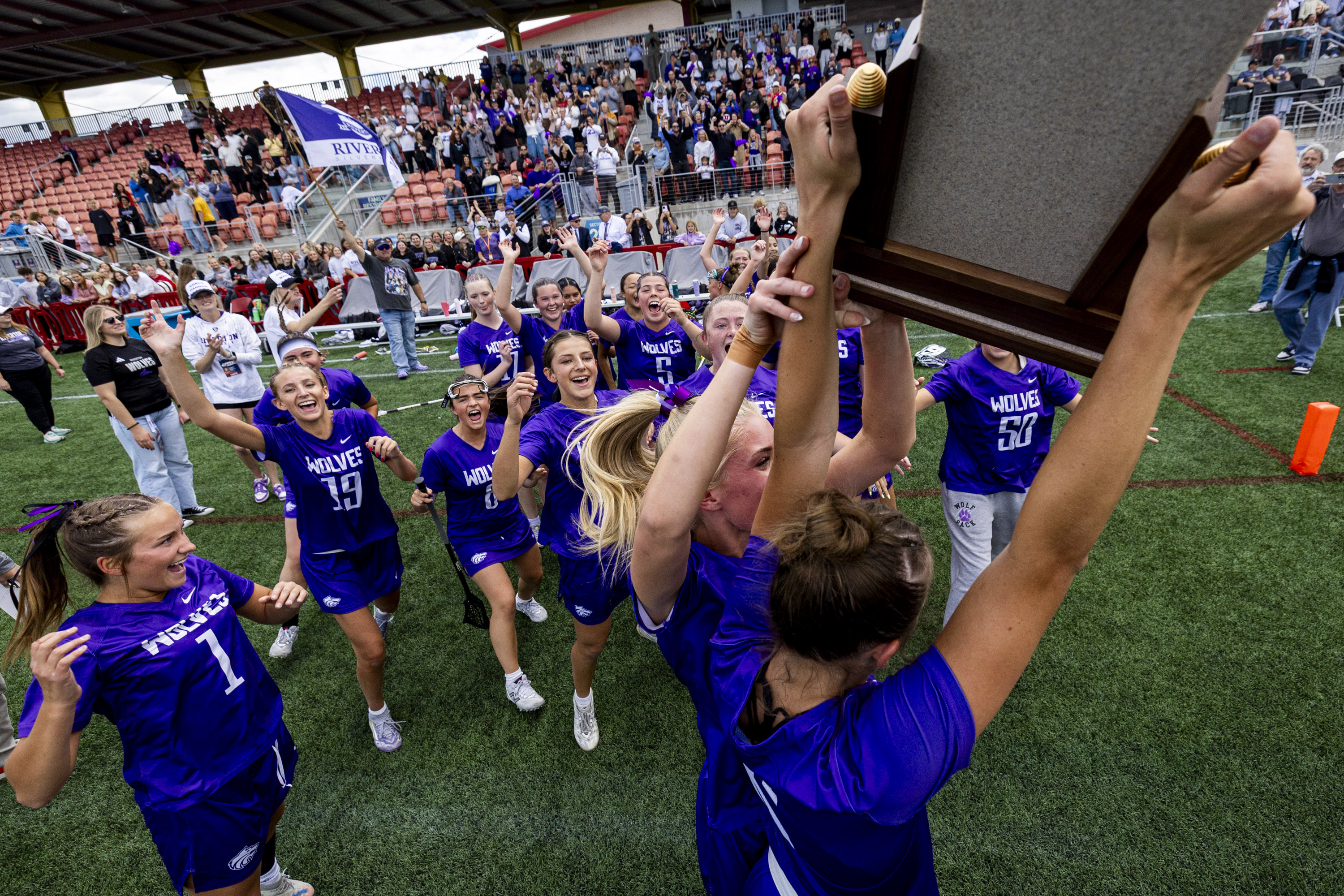 Riverton players celebrate around the championship trophy after defeating Skyridge in overtime during the 6A girls lacrosse state championship game, held at Zions Bank Stadium in Herriman on Thursday, May 21, 2026.
