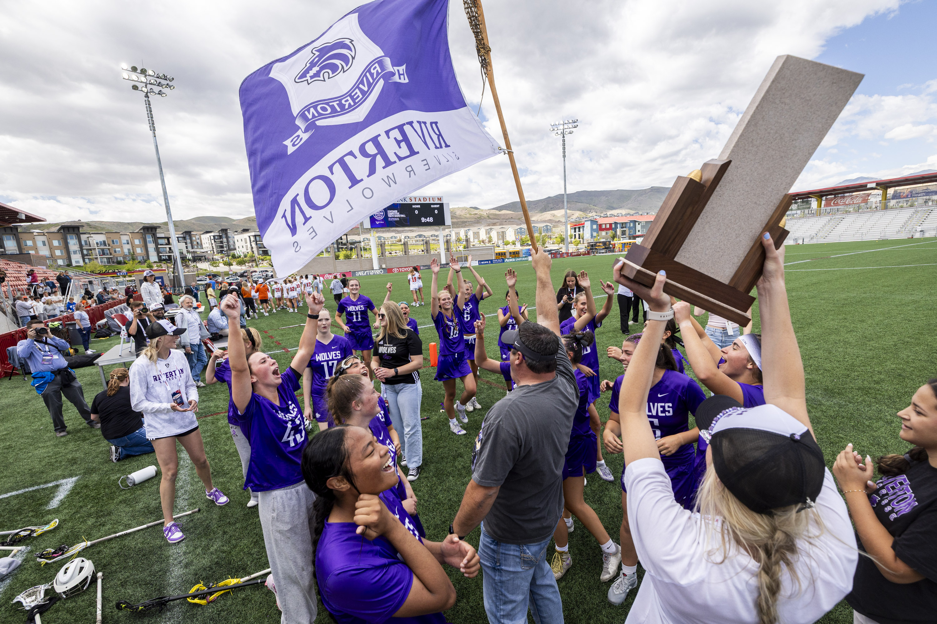 Riverton players celebrate around the championship trophy after defeating Skyridge in overtime during the 6A girls lacrosse state championship game, held at Zions Bank Stadium in Herriman on Thursday, May 21, 2026.