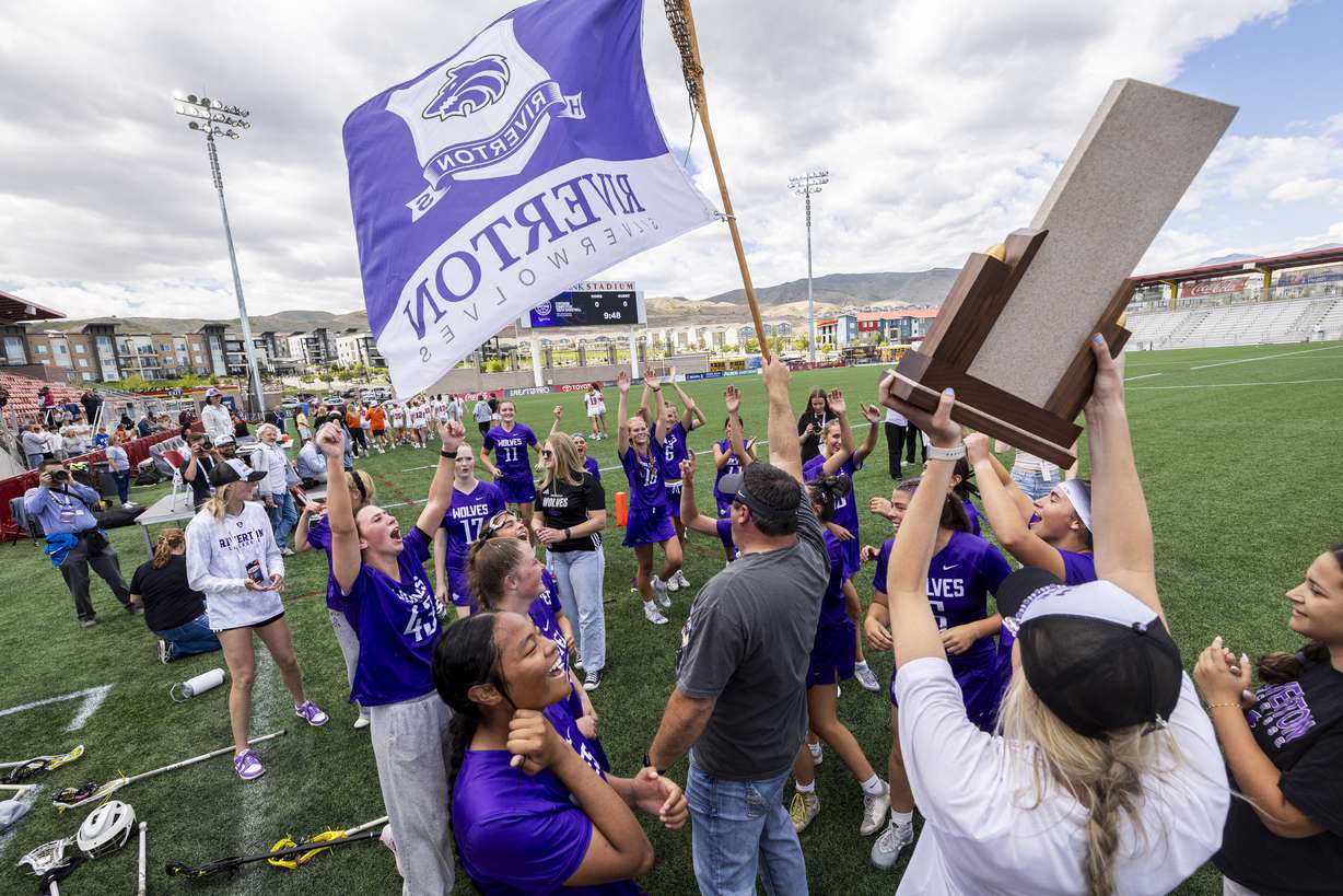 Riverton players celebrate around the championship trophy after defeating Skyridge in overtime during the 6A girls lacrosse state championship game, held at Zions Bank Stadium in Herriman on Thursday, May 21, 2026.