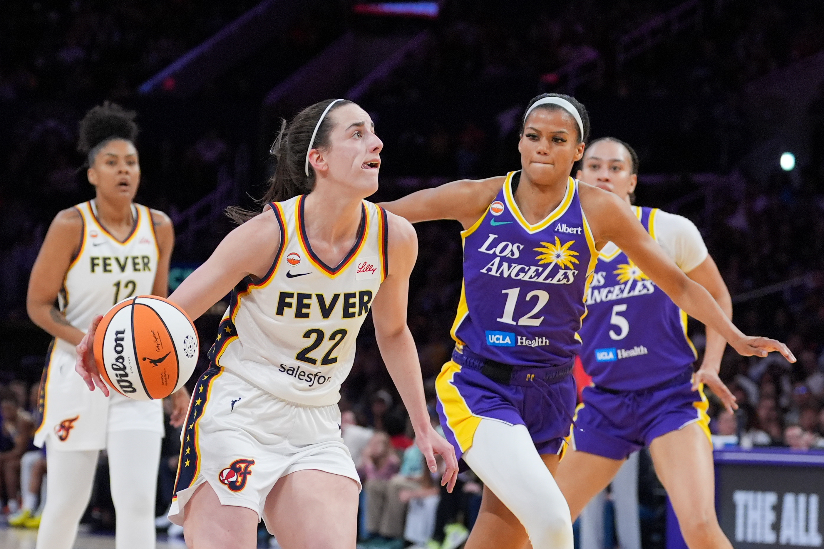 Indiana Fever guard Caitlin Clark (22) drives past Los Angeles Sparks guard-forward Rae Burrell (12) during the first half of a WNBA basketball game Wednesday, May 13, 2026, in Los Angeles. 
