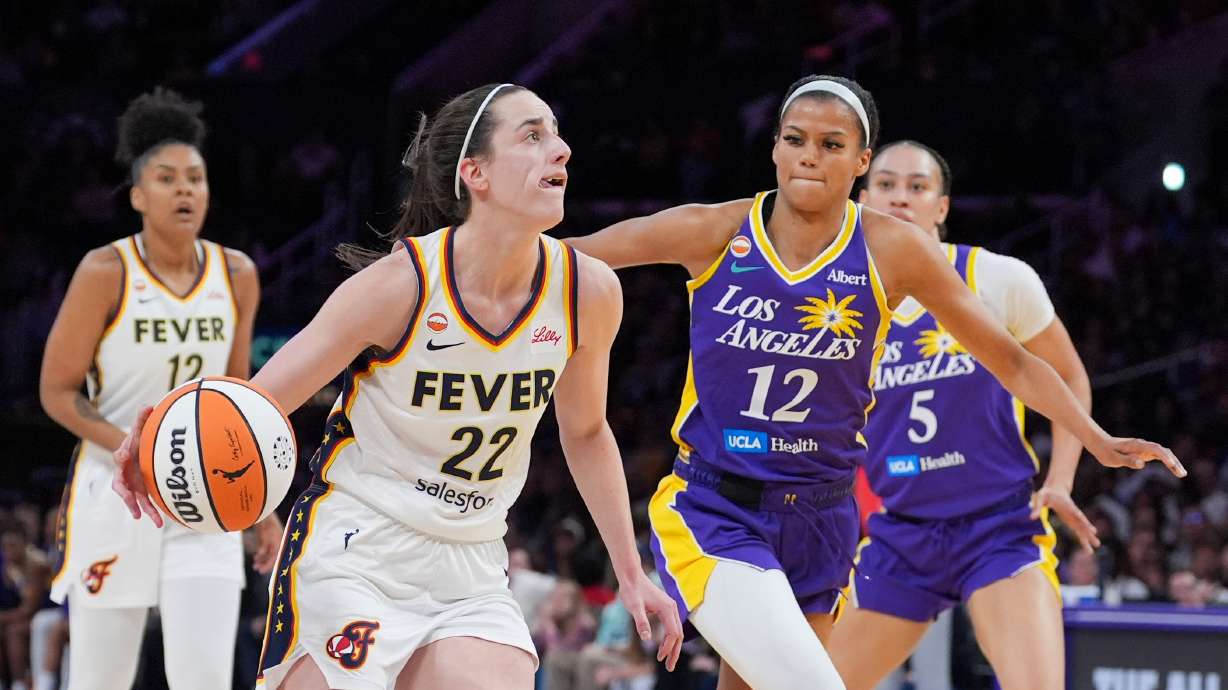Indiana Fever guard Caitlin Clark (22) drives past Los Angeles Sparks guard-forward Rae Burrell (12) during the first half of a WNBA basketball game Wednesday, May 13, 2026, in Los Angeles.