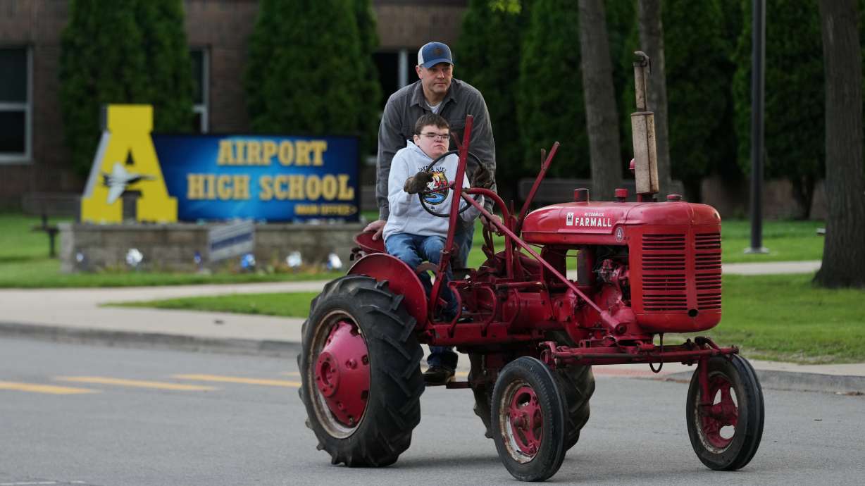 Austin Neddo drives a 1940 Farmall A tractor with his father, Shay, during Tractor Day for graduating seniors at Airport High School, Friday, in Carleton, Mich. Tractor Day is a school tradition that dates back to the 1980s.
