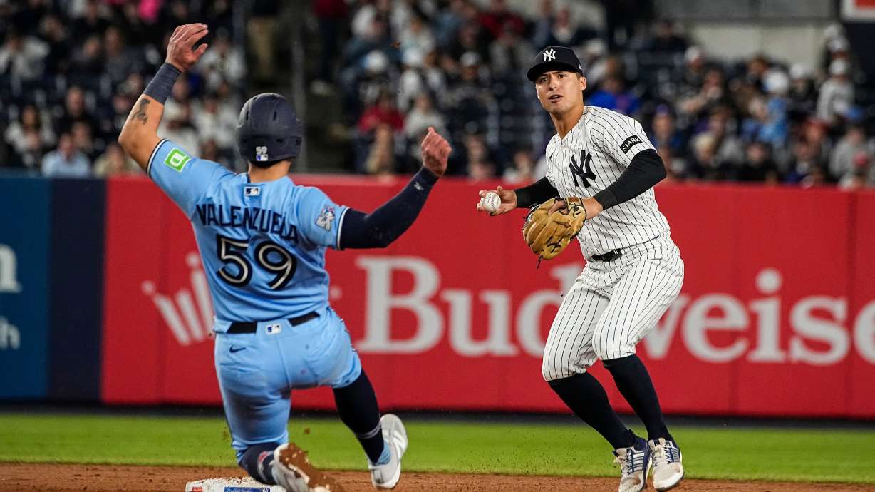 New York Yankees shortstop Anthony Volpe, right, throws to first base after forcing Toronto Blue Jays Brandon Valenzuela (59) out at second base on a double play, during the ninth inning of a baseball game, Thursday, May 21, 2026. in New York.