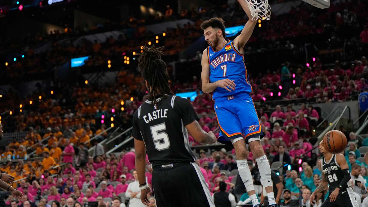 Oklahoma City Thunder center Chet Holmgren (7) hangs on the rim next to San Antonio Spurs guard Stephon Castle (5) after a dunk during the second half of Game 3 in the Western Conference finals NBA basketball playoffs series Friday, May 22, 2026, in San Antonio.