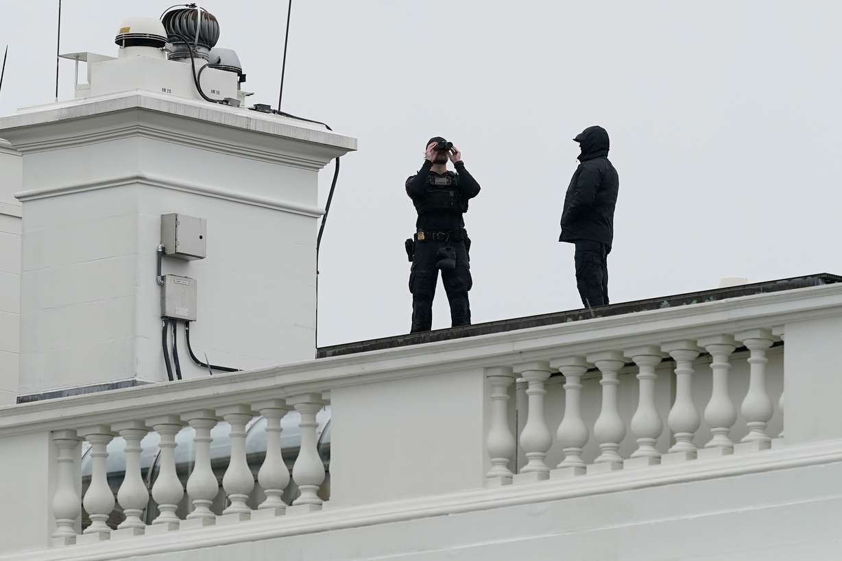 Secret Service police observe from the roof of the White House, Saturday, in Washington, after reports of shots fired near the White House. It marked the third time in the past month that gunfire was near President Donald Trump.