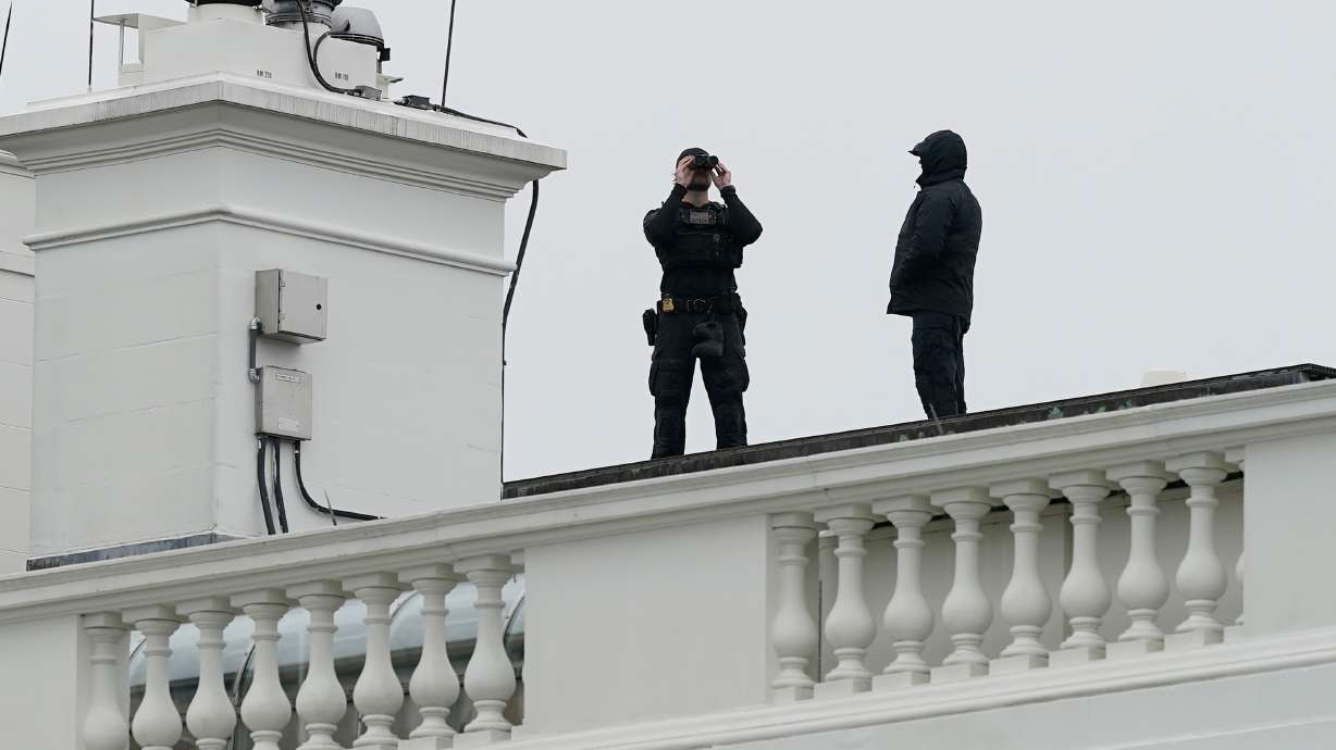 Secret Service police observe from the roof of the White House, Saturday, in Washington, after reports of shots fired near the White House. A law enforcement official said the Secret Service shot a person near the White House.