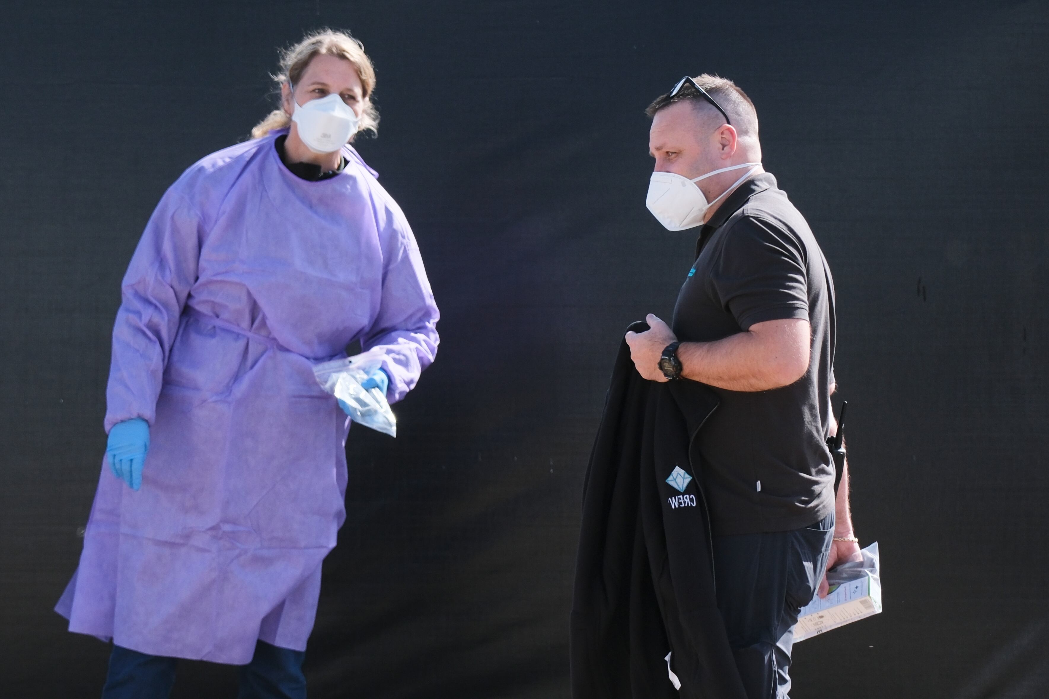 A crew member walks by a woman in protective clothing after disembarking from the MV Hondius cruise ship after its arrival at the Port of Rotterdam, Netherlands, May 18. The ship arrived back in the Netherlands after its protacted journey.