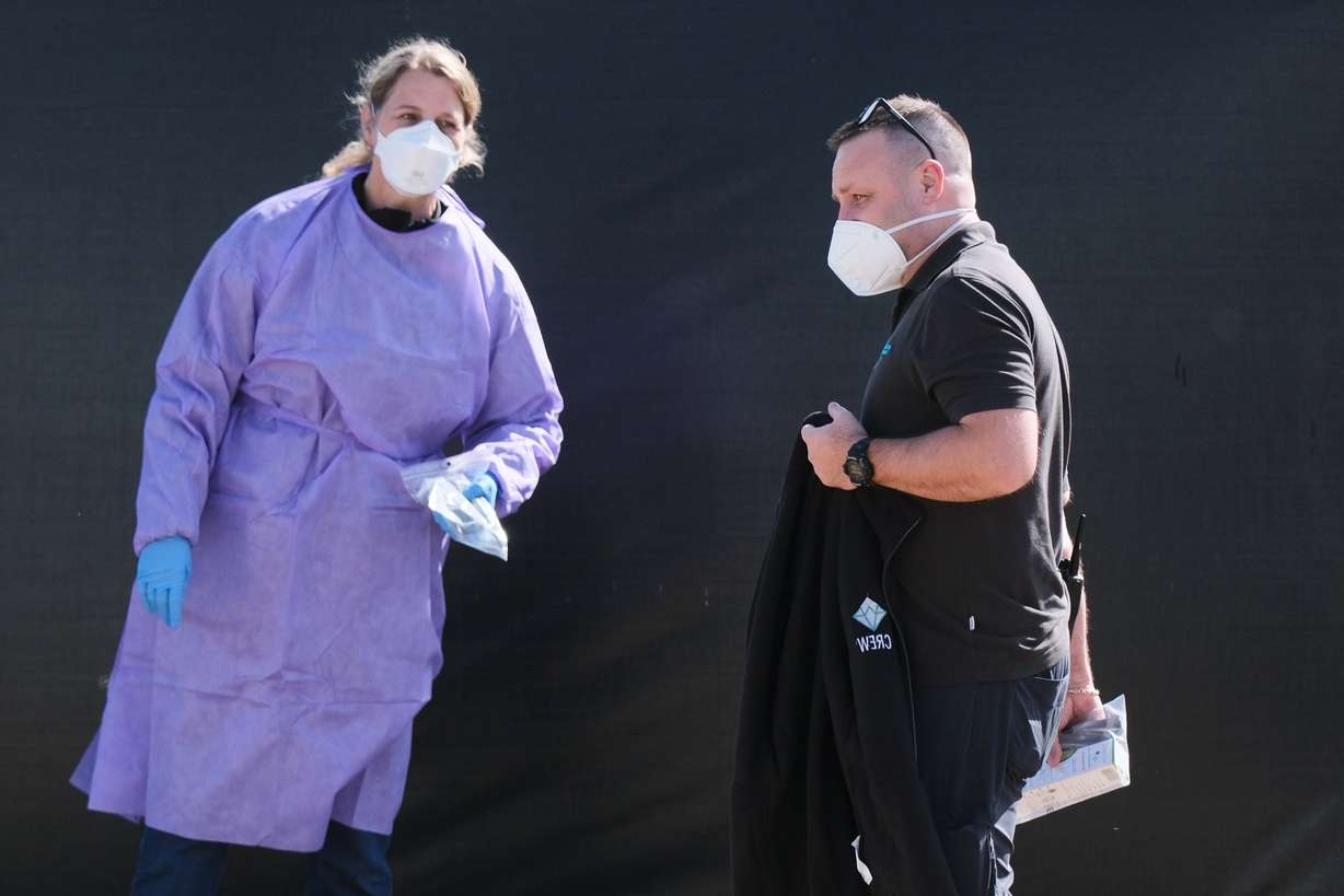 A crew member walks by a woman in protective clothing after disembarking from the MV Hondius cruise ship after its arrival at the Port of Rotterdam, Netherlands, May 18. The ship arrived back in the Netherlands after its protacted journey.