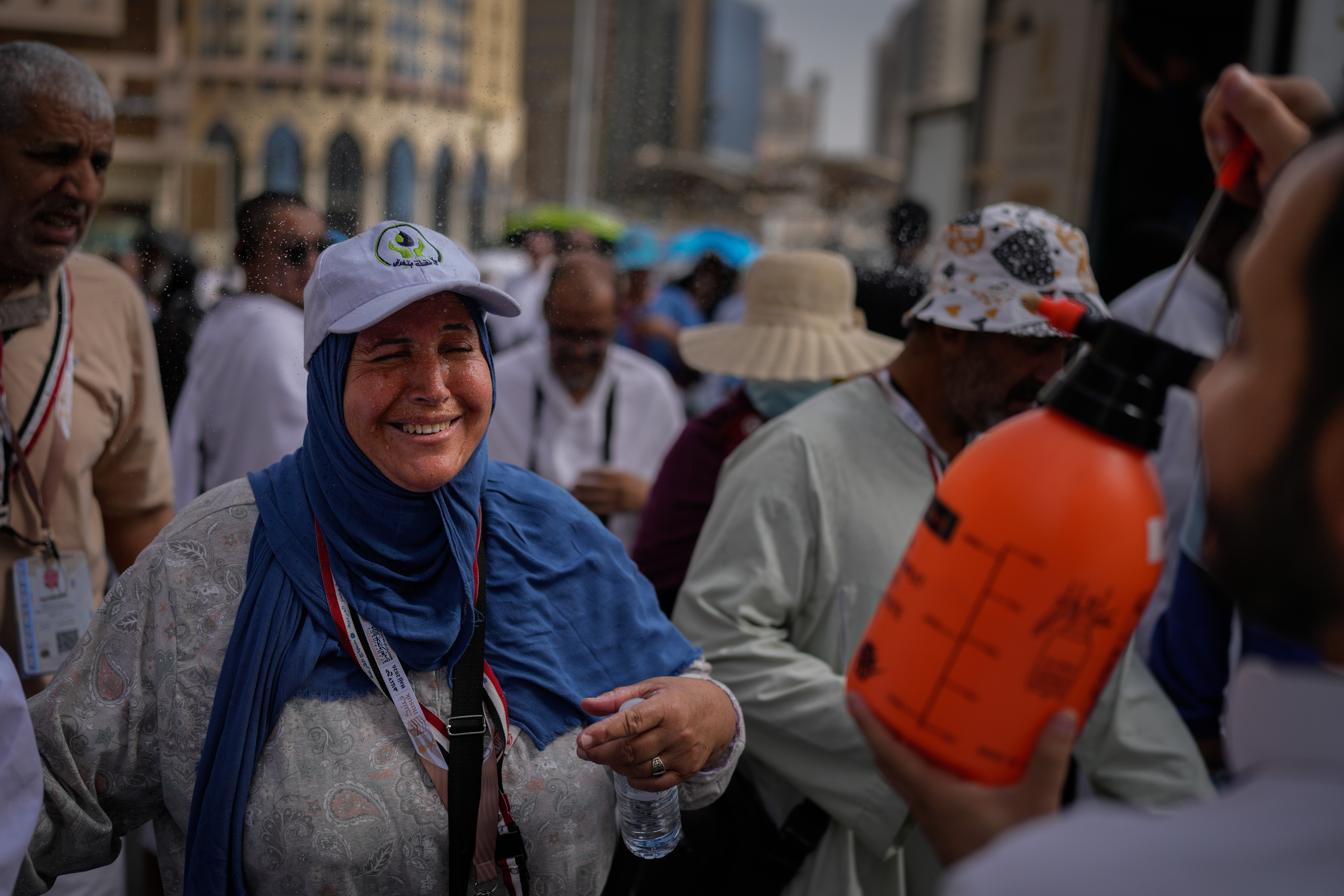 A Muslim pilgrim reacts as a volunteer sprays water to cool them outside the Grand Mosque during the annual hajj pilgrimage at the holy city of Mecca, Saudi Arabia, Sunday. The pilgrimage began Monday amid the heat and regional tensions.