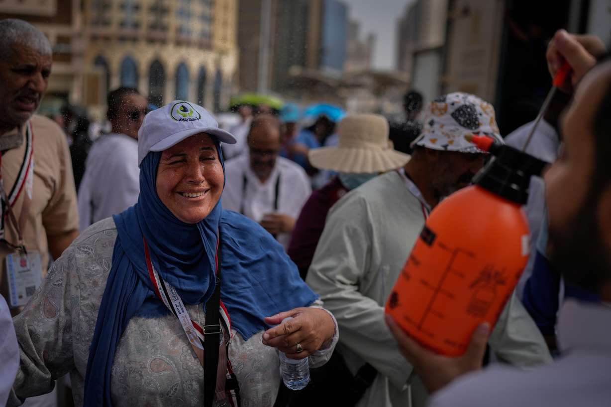 A Muslim pilgrim reacts as a volunteer sprays water to cool them outside the Grand Mosque during the annual hajj pilgrimage at the holy city of Mecca, Saudi Arabia, Sunday. The pilgrimage began Monday amid the heat and regional tensions.