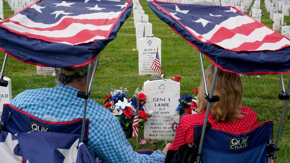 Eugene and Linda Lamie, of Homerville, Ga., sit by the grave of their son U.S. Army Sgt. Gene Lamie in Section 60 at Arlington National Cemetery on Memorial Day, May 29, 2023, in Arlington, Va.