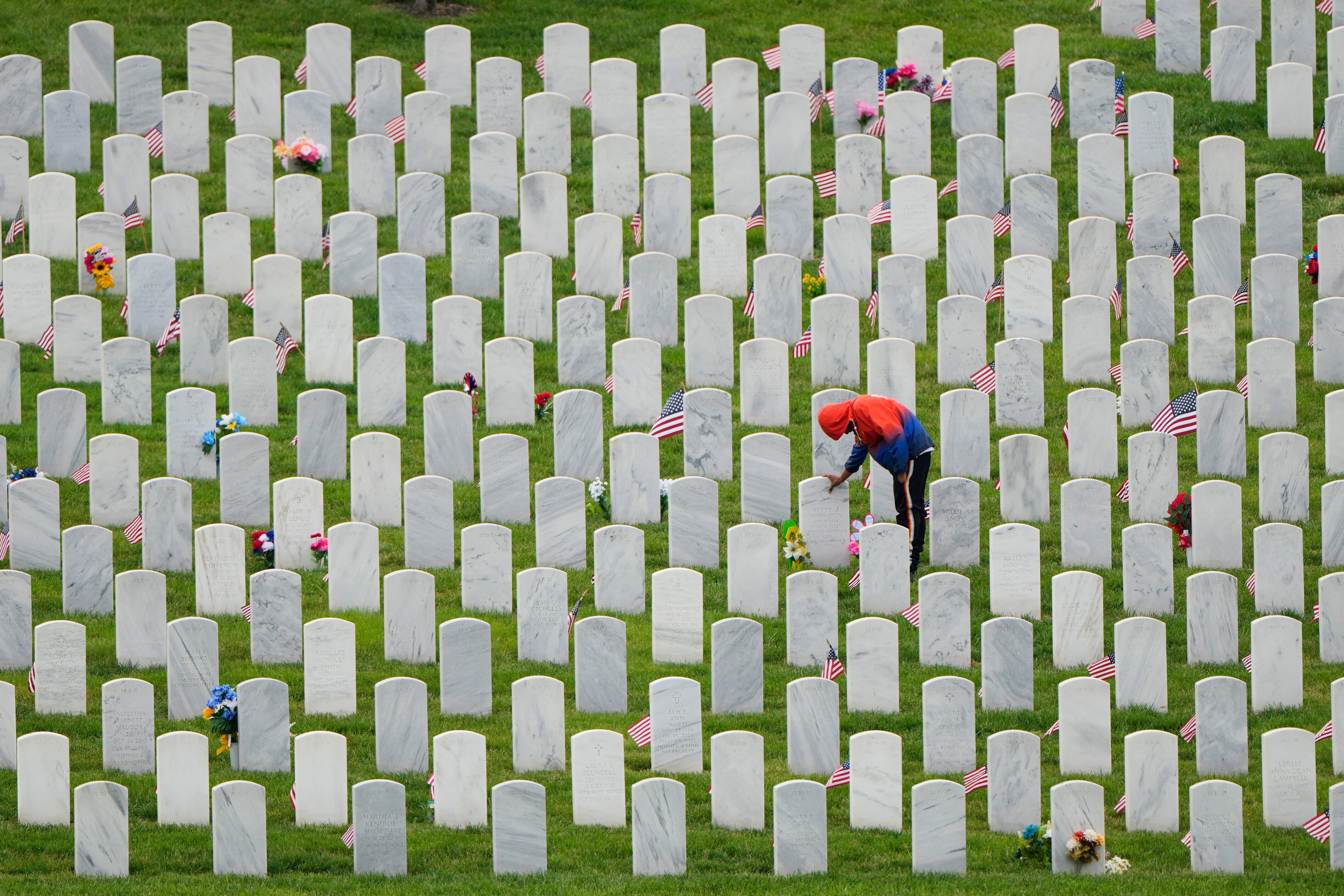 Richard Cross touches his grandmother's headstone while visiting Leavenworth National Cemetery on the eve of Memorial Day, May 25, 2025, in Leavenworth, Kan.