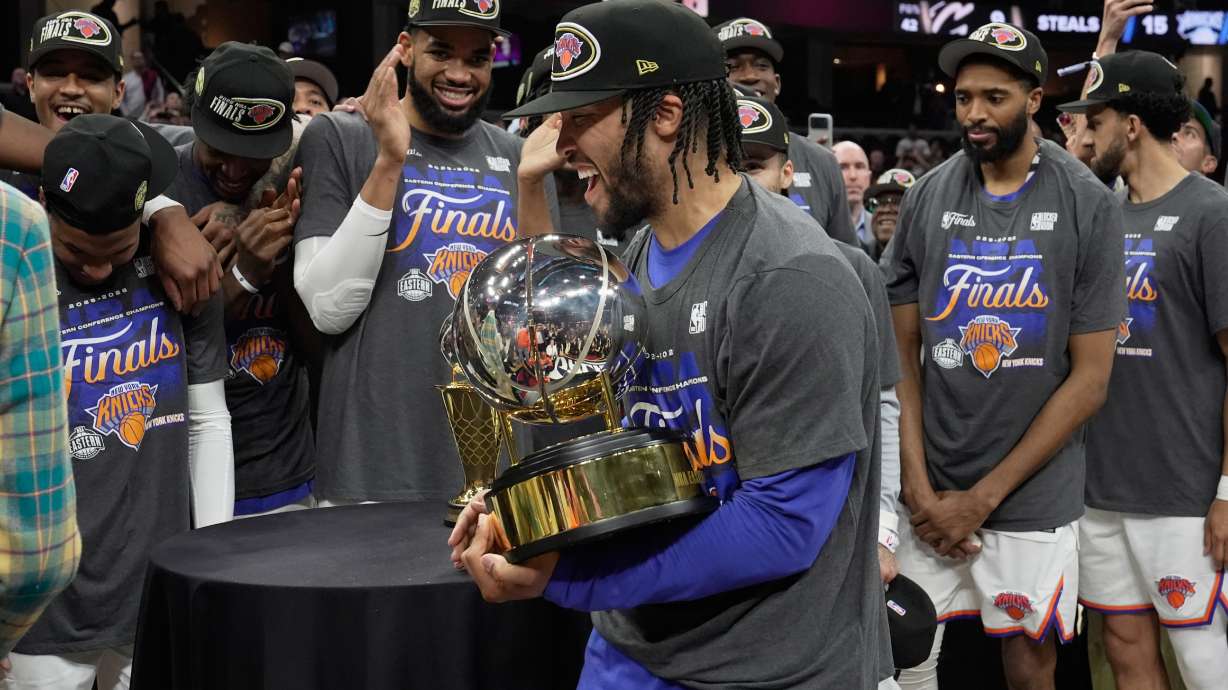 New York Knicks guard Jalen Brunson, center, holds the Eastern Conference Championship trophy after Game 4 in the Eastern Conference finals NBA basketball playoffs series against the Cleveland Cavaliers in Cleveland, Monday, May 25, 2026.