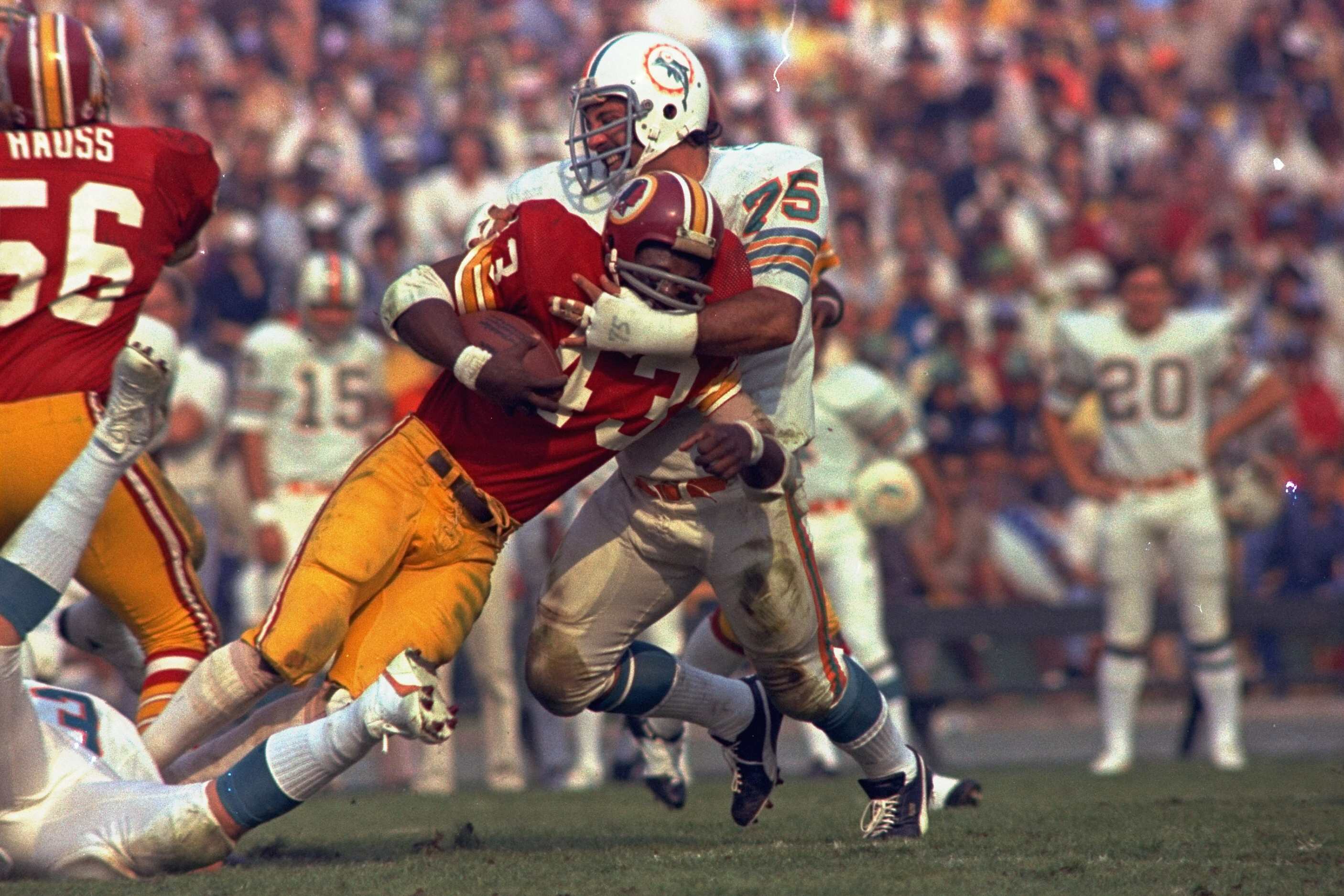 Washington Redskins running back Larry Brown (43) is stopped in his tracks by Miami Dolphins defender Manny Fernandez (75) during the NFL football Super Bowl VII game in Los Angeles, Jan. 14, 1973. 