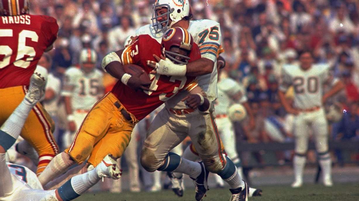 Washington Redskins running back Larry Brown (43) is stopped in his tracks by Miami Dolphins defender Manny Fernandez (75) during the NFL football Super Bowl VII game in Los Angeles, Jan. 14, 1973.