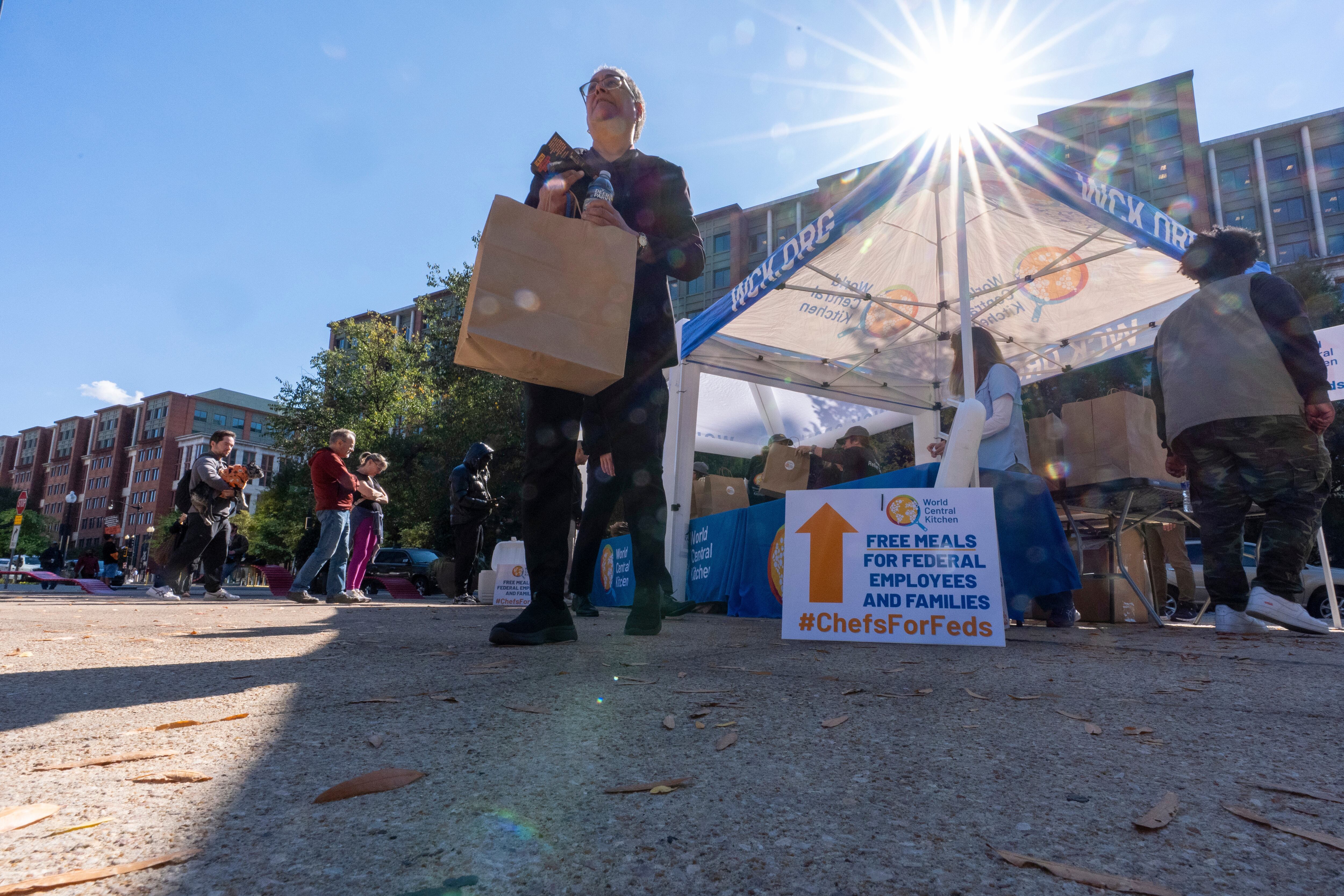 A person walks with a meal from chef Jose Andres' World Central Kitchen as they distribute more than 1100 meals for federal workers and their families in Canal Park, Oct. 27, in Washington. A bipartisan group of senators proposed a bill to keep Congress in Washington during future shutdowns.