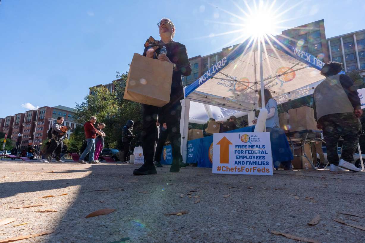 A person walks with a meal from chef Jose Andres' World Central Kitchen as they distribute more than 1100 meals for federal workers and their families in Canal Park, Oct. 27, in Washington. A bipartisan group of senators proposed a bill to keep Congress in Washington during future shutdowns.
