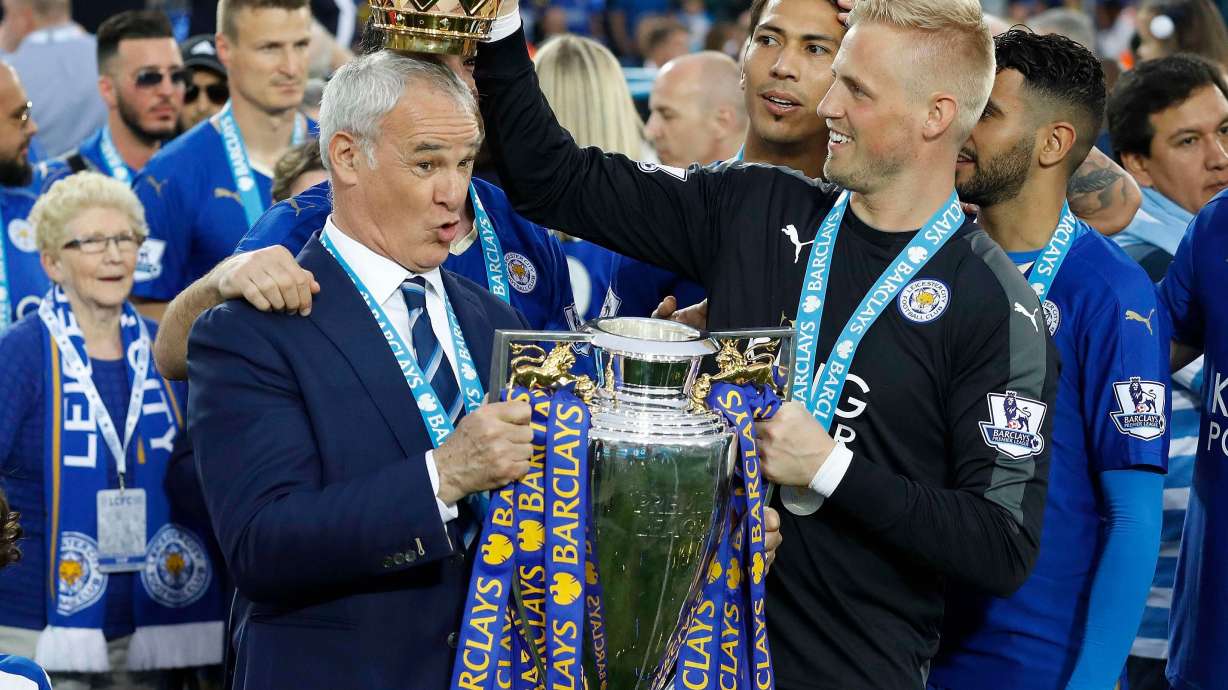 FILE - Leicester City team manager Claudio Ranieri has the crown of the trophy placed on his head by Leicester goalkeeper Kasper Schmeichel as they celebrate becoming the English Premier League soccer champions at King Power stadium in Leicester, England, May 7, 2016.