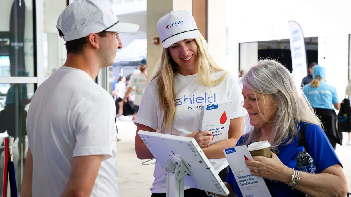 Jamie Calmet, Guardant Health, discusses the importance of colorectal cancer screening and the Shield test as a new screening option with a participant at the Dolphins Cancer Challenge on Feb. 22, 2025, in Miami Gardens, Fla.