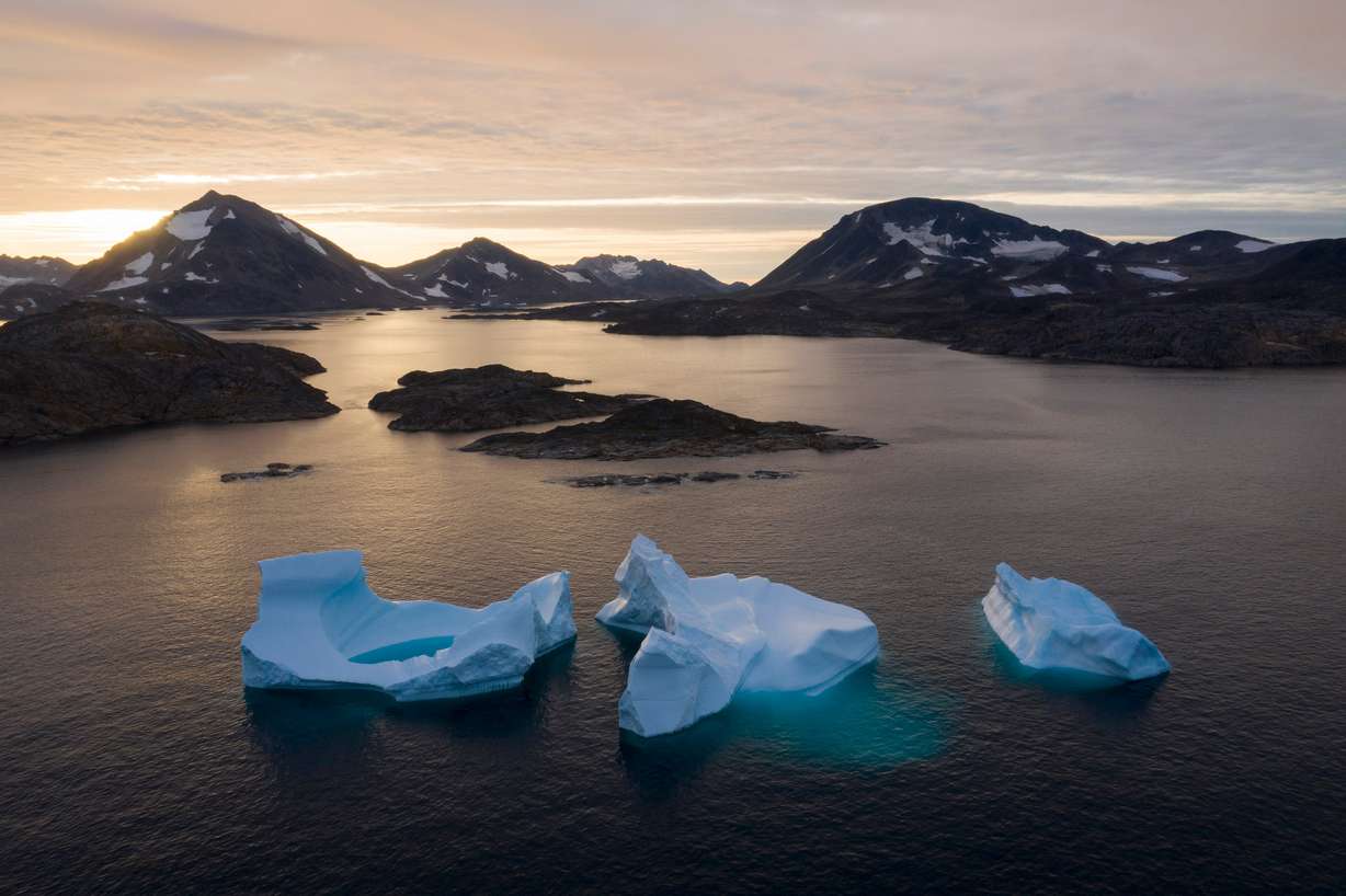 Large icebergs float away as the sun rises near Kulusuk, Greenland, on Aug. 16, 2019. A new United Nations climate projection says Arctic sea ice could shrink further this summer.