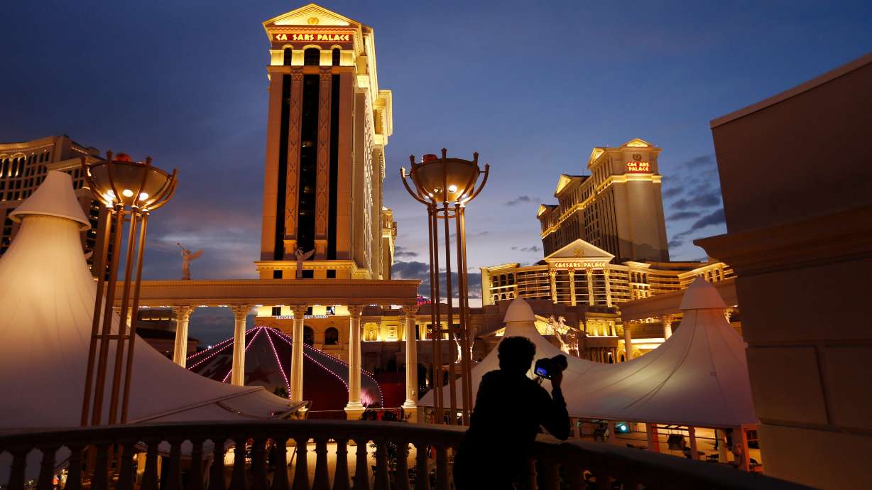 A man photographs Caesars Palace hotel and casino in Las Vegas, Jan. 12, 2015. Caesars Entertainment is being acquired by Fertitta for almost $6 billion.