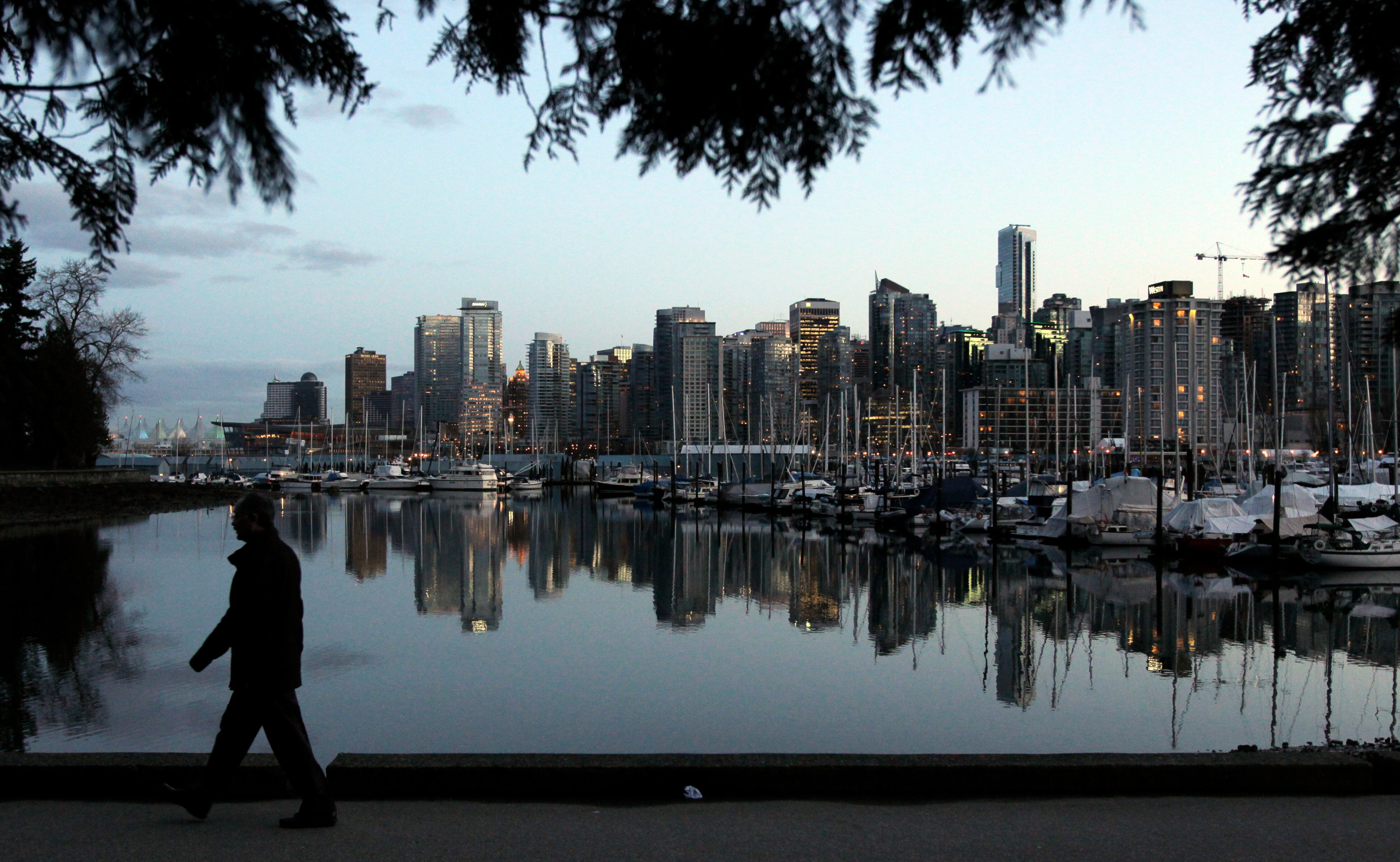 A man walks in Stanley Park as the skyline of Vancouver is reflected in water in Vancouver, British Columbia, Feb. 5, 2010. Vancouver announced its push for an MLB team last month.